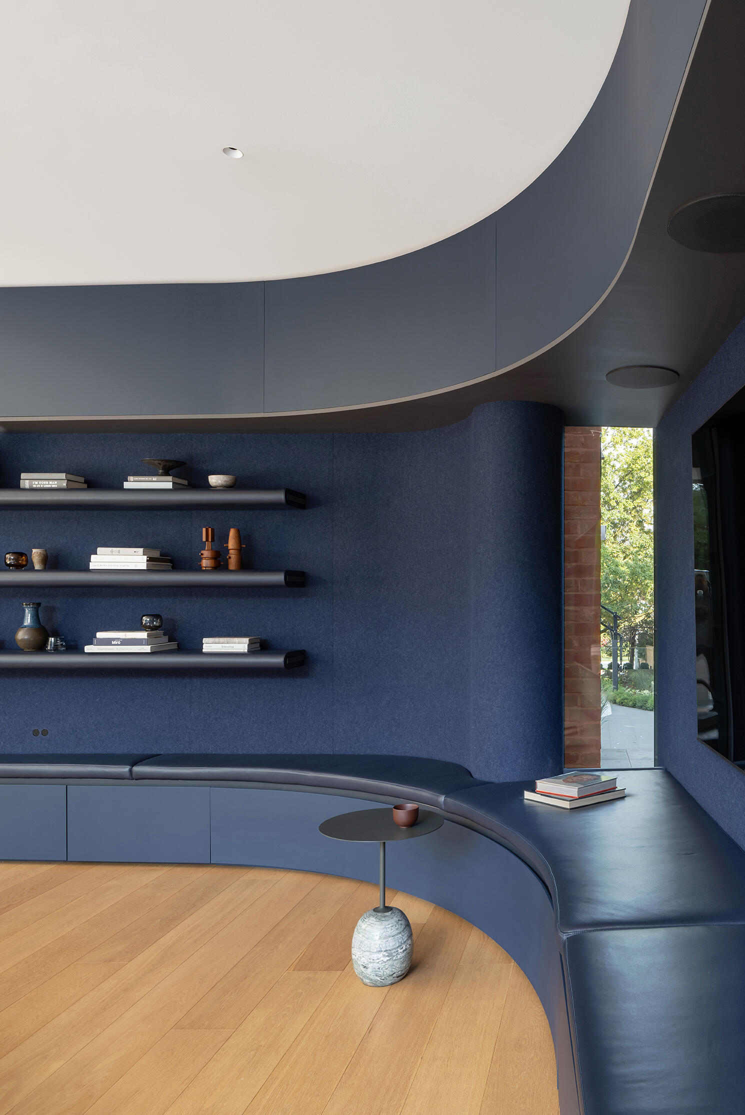 A cozy blue family room with felt-lined cabinetry, curved walls, and a garden connection inside the new glass addition.