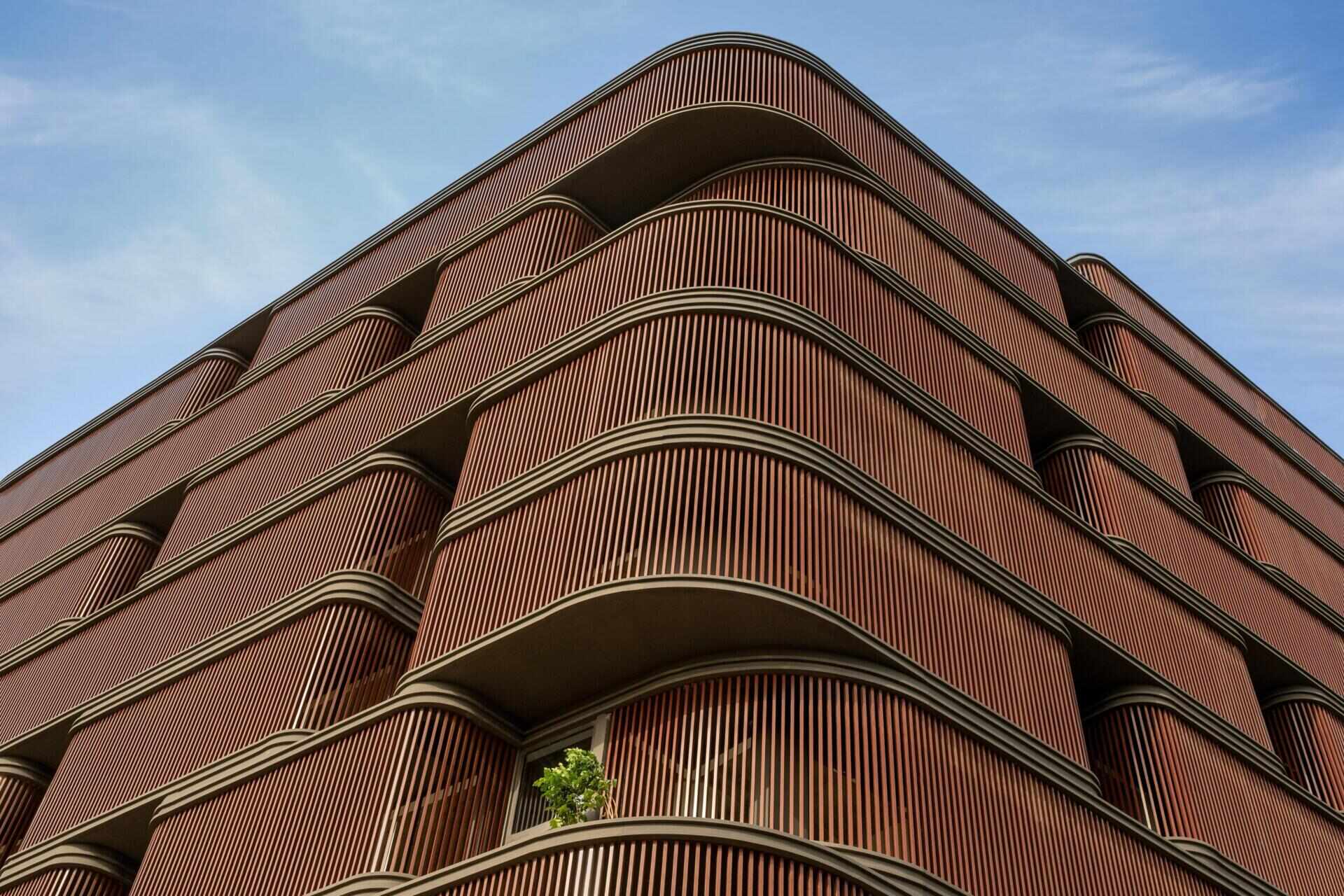 This office building combines capsule-shaped architecture, flexible workspaces, rooftop gardens, planter terraces, natural ventilation, and passive cooling strategies to create a greener, more comfortable workplace in one of India's hottest climates.