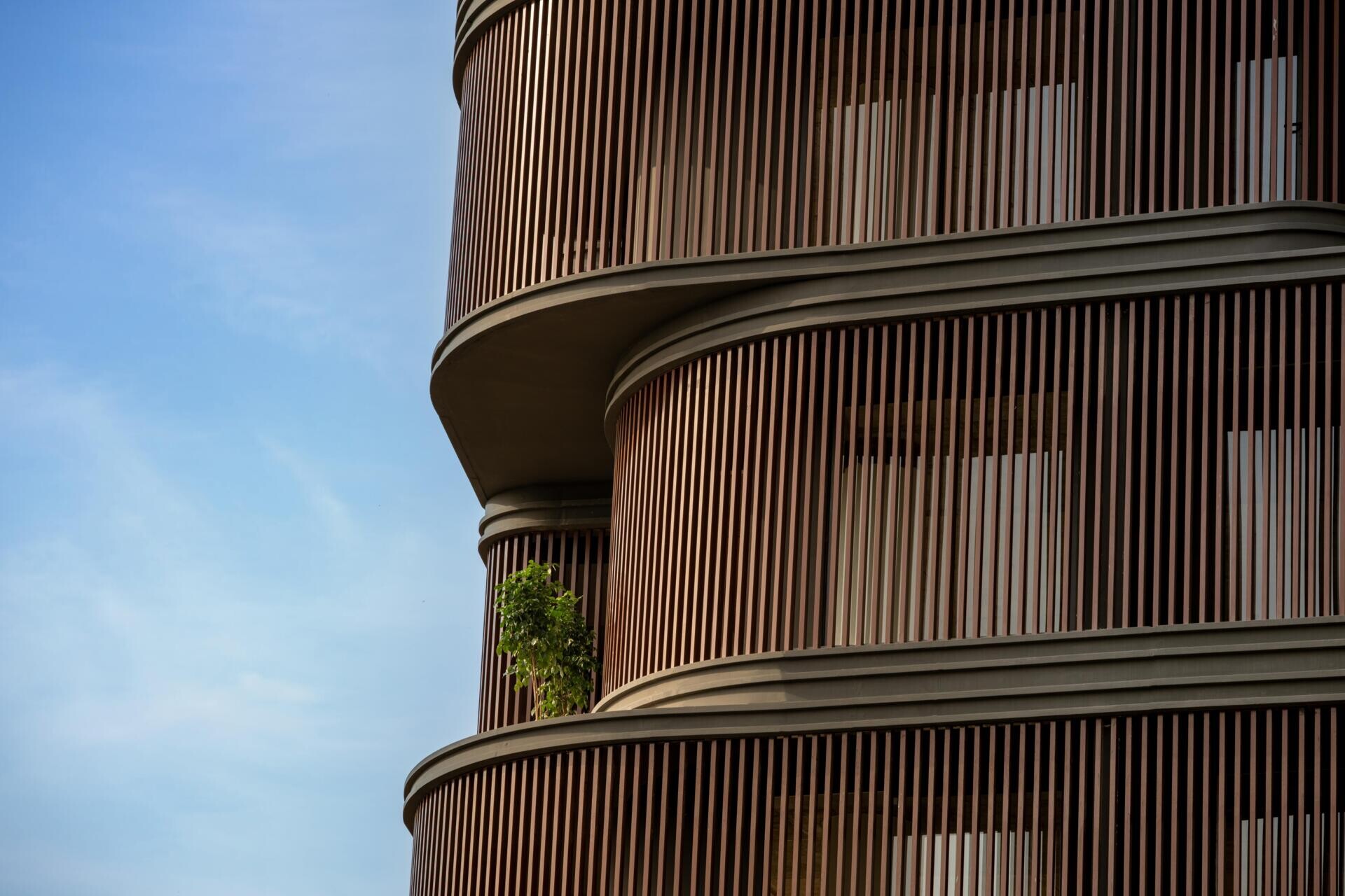 This office building combines capsule-shaped architecture, flexible workspaces, rooftop gardens, planter terraces, natural ventilation, and passive cooling strategies to create a greener, more comfortable workplace in one of India's hottest climates.