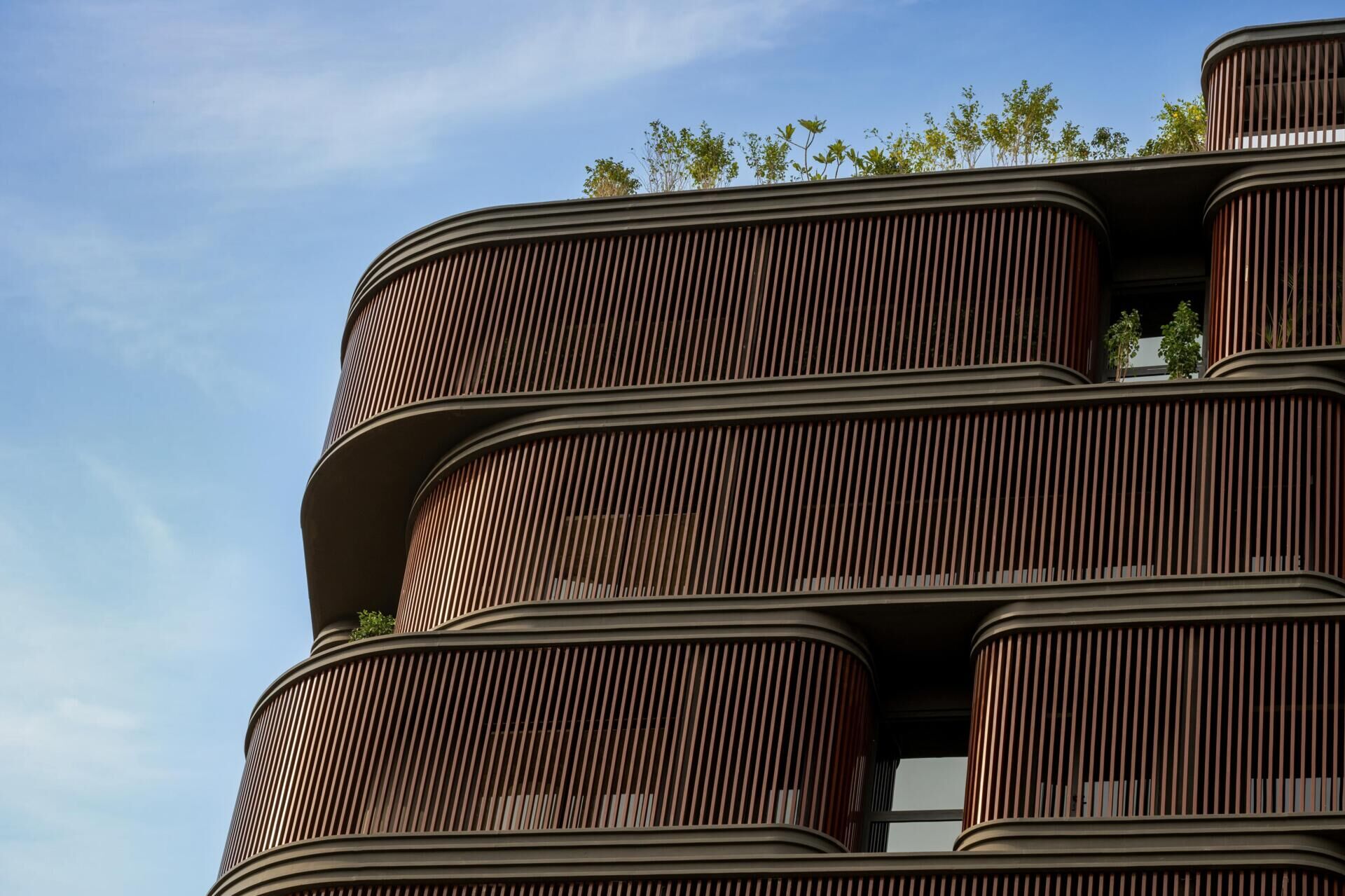 This office building combines capsule-shaped architecture, flexible workspaces, rooftop gardens, planter terraces, natural ventilation, and passive cooling strategies to create a greener, more comfortable workplace in one of India's hottest climates.