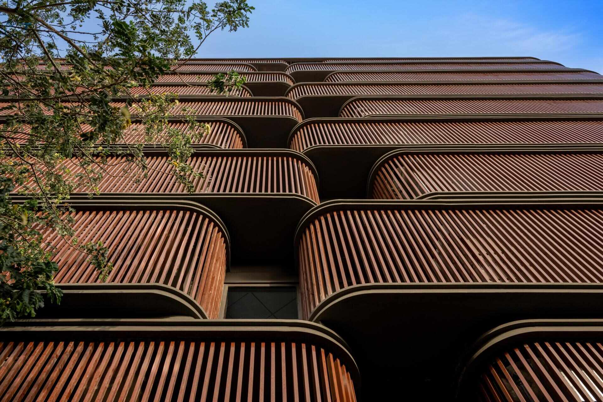 This office building combines capsule-shaped architecture, flexible workspaces, rooftop gardens, planter terraces, natural ventilation, and passive cooling strategies to create a greener, more comfortable workplace in one of India's hottest climates.