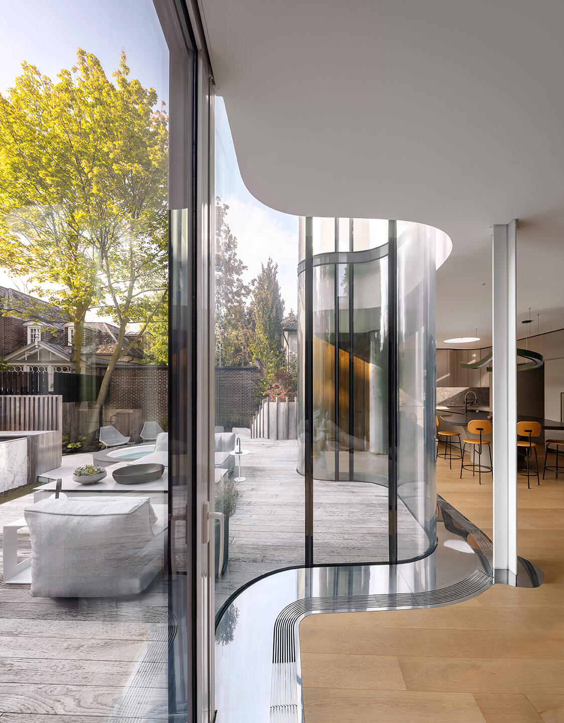 The flowing curved glass wall is the signature feature of Snider House, bringing light, transparency, and garden views deep into the home.
