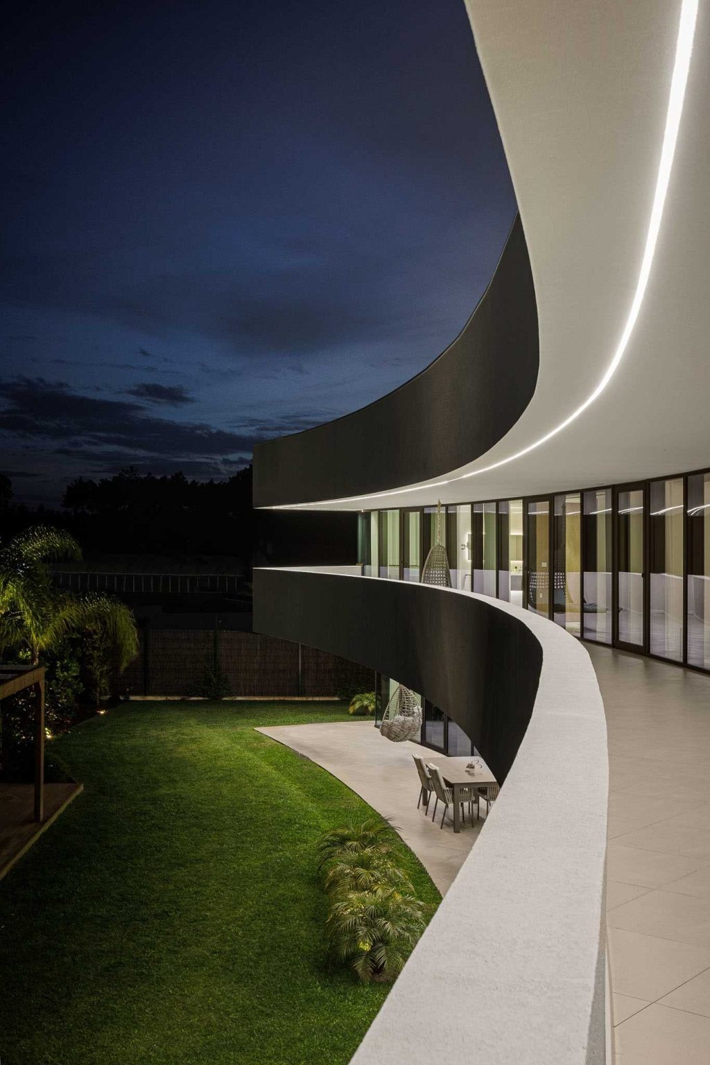 Integrated exterior lighting highlights the home's sweeping architecture after sunset, revealing the elegant curve from an entirely new perspective.