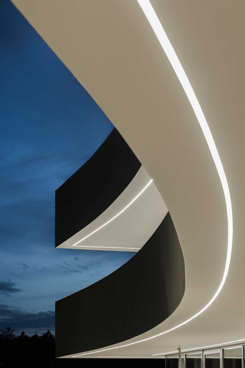Integrated exterior lighting highlights the home's sweeping architecture after sunset, revealing the elegant curve from an entirely new perspective.