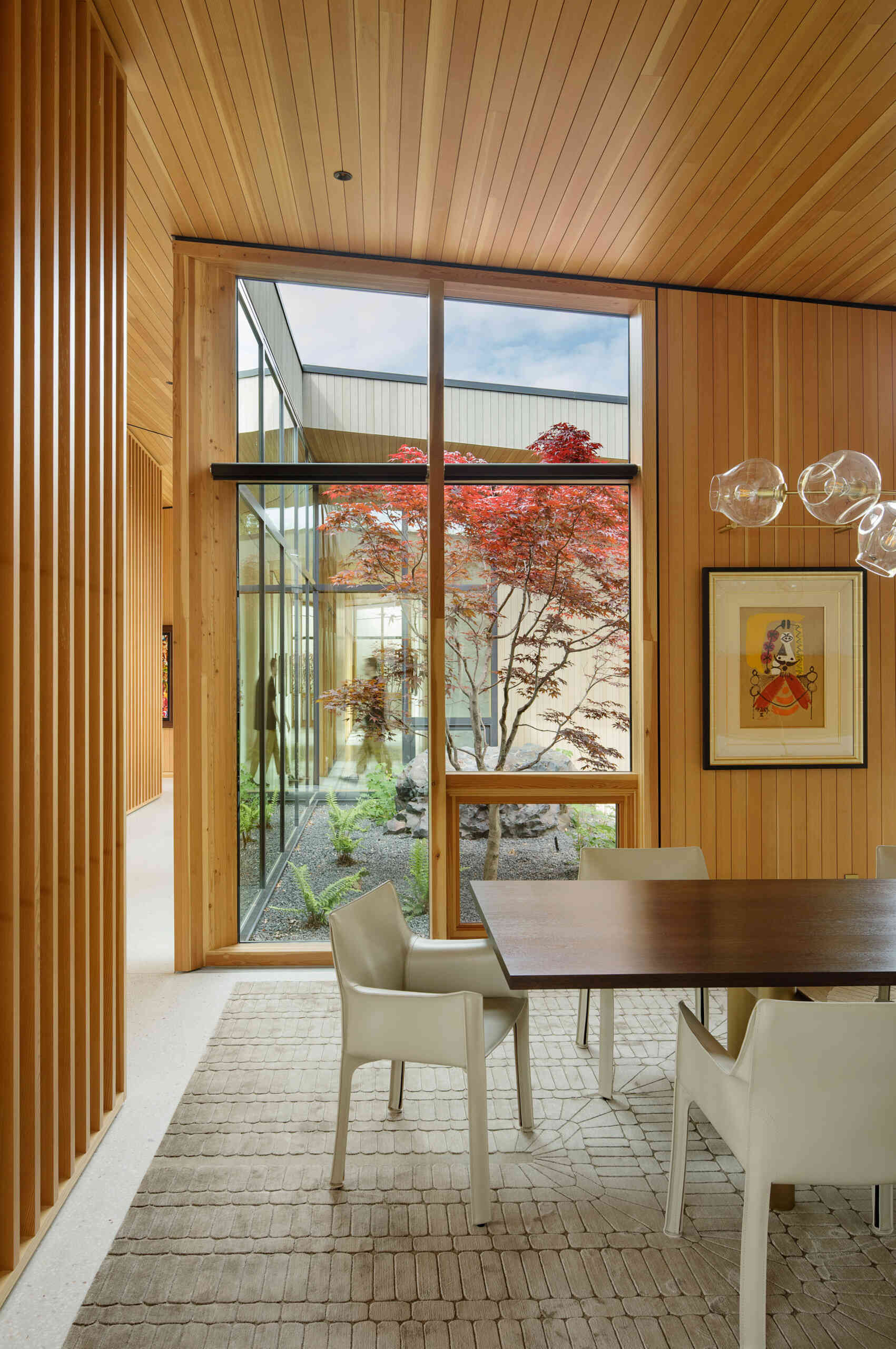 Eche un vistazo al interior del cálido comedor de madera, donde las altas ventanas, la suave luz natural y los elegantes acabados crean el ambiente perfecto para cenar y entretenerse todos los días.