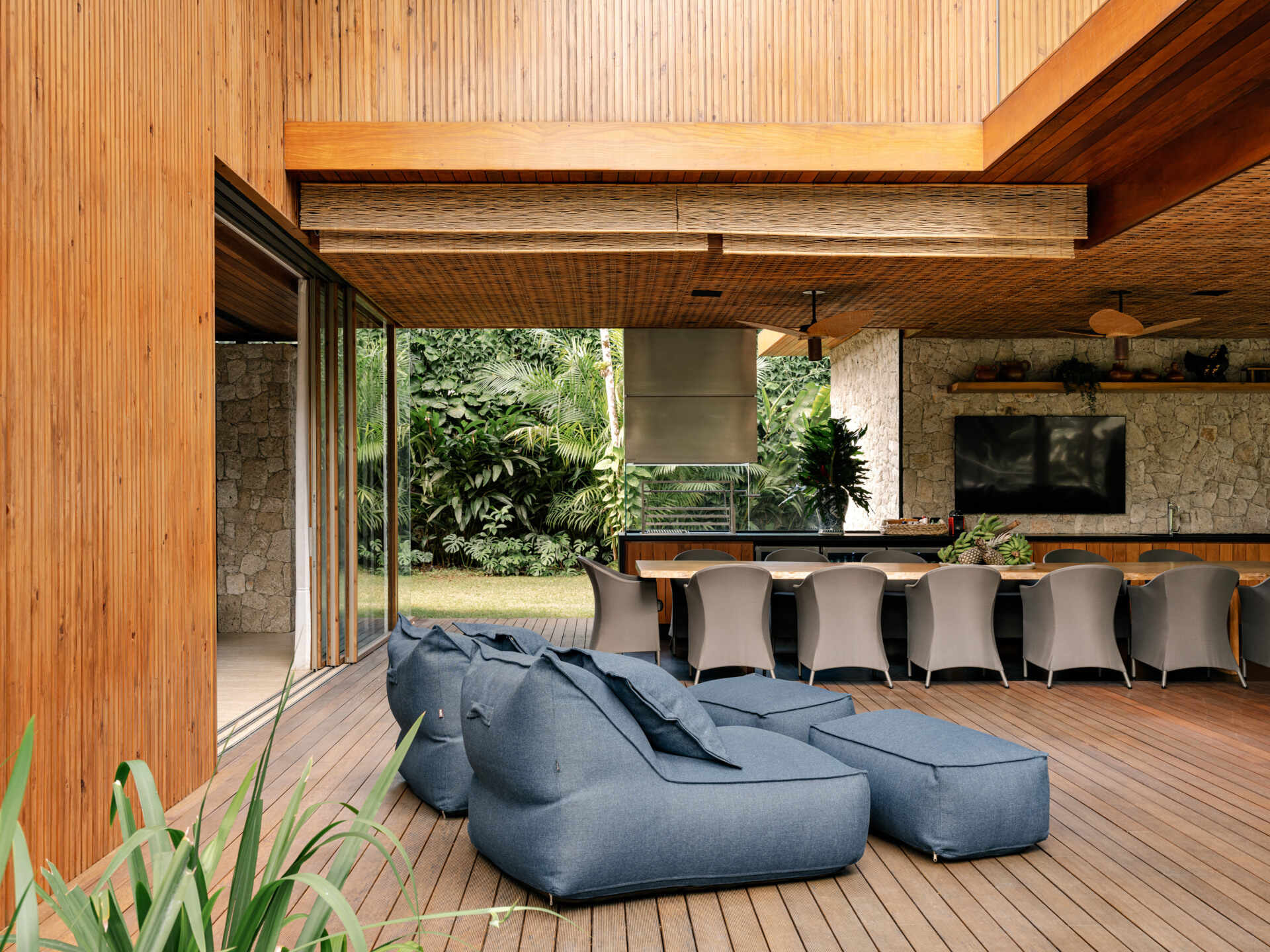 Tour an outdoor entertaining space with a huge timber dining table, barbecue area, lounge seating, and poolside views.