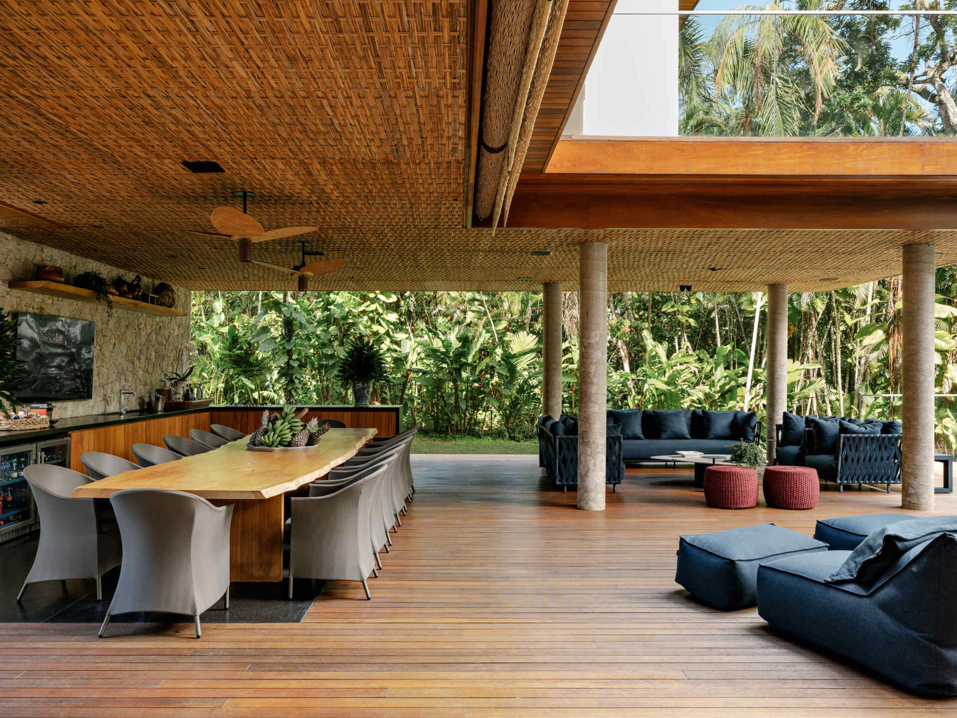 Tour an outdoor entertaining space with a huge timber dining table, barbecue area, lounge seating, and poolside views.
