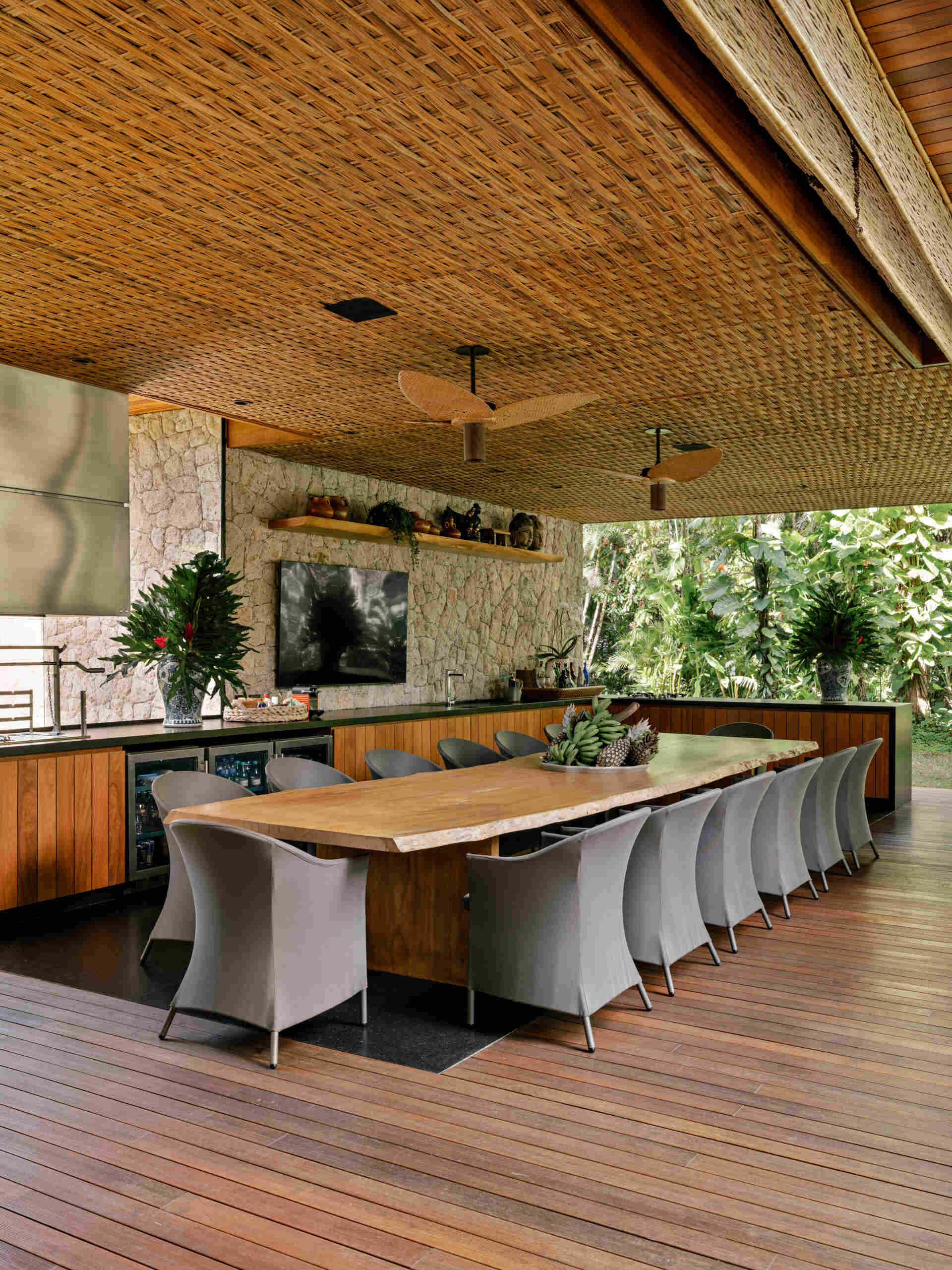 Tour an outdoor entertaining space with a huge timber dining table, barbecue area, lounge seating, and poolside views.