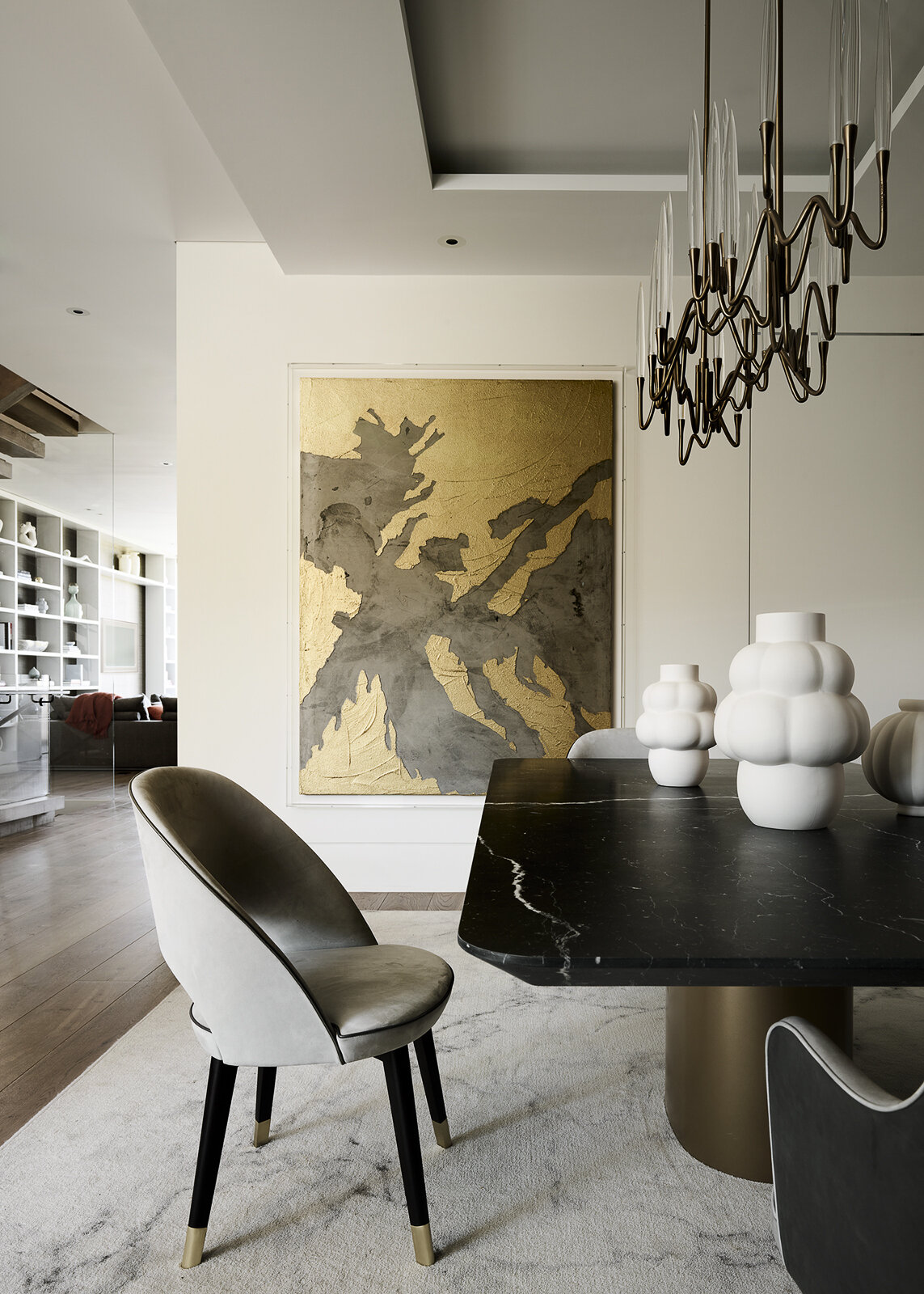 A shimmering metallic artwork becomes the centerpiece of this contemporary dining room, catching natural light and casting a warm glow throughout the space. Paired with sculptural lighting and refined furnishings, it creates an elegant setting where art and everyday living come together.