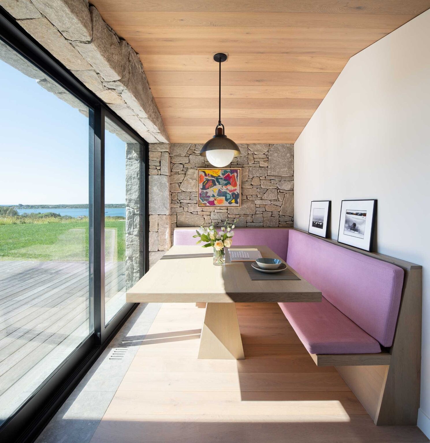 Built-in banquette seating, a quiet lounge, and stone walls throughout the home create warm, inviting spaces with beautiful pool and water views.