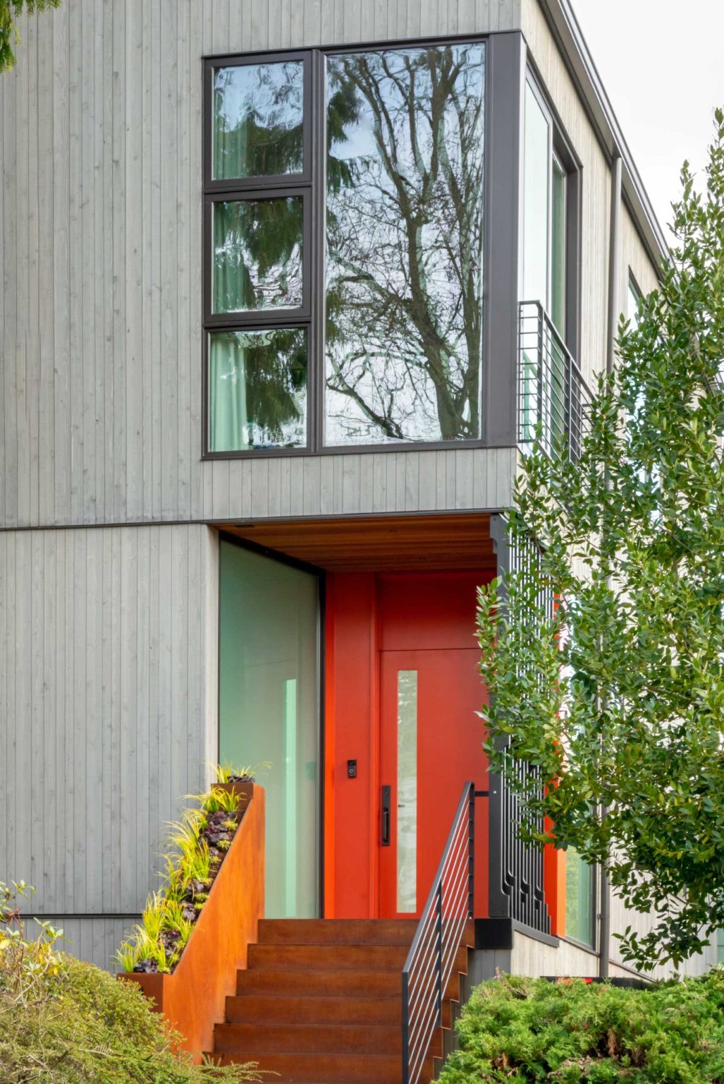 A colorful new front entry, warm wood siding, larger windows, and a welcoming façade completely change the street presence of this renovated Seattle home.