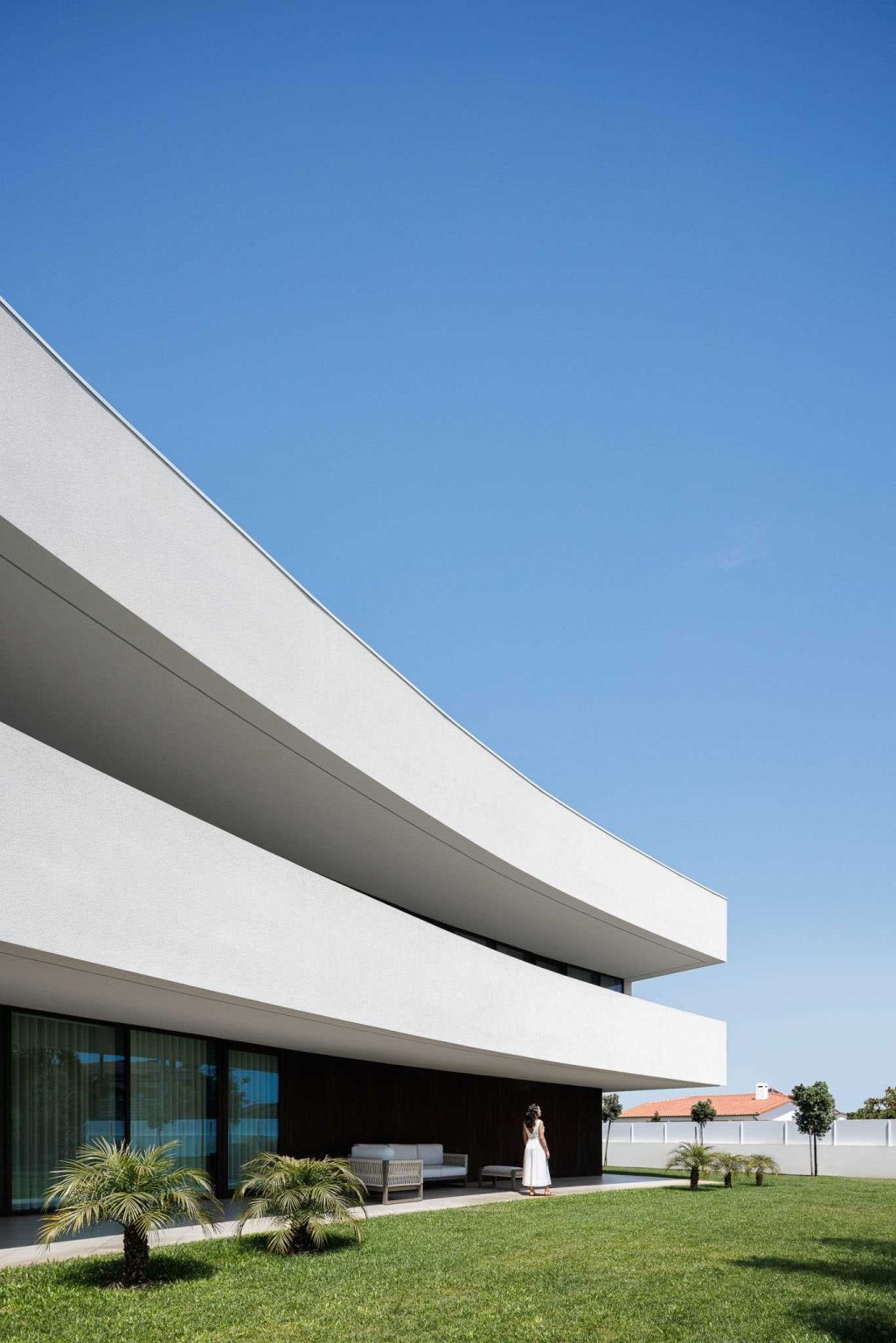 See how one sweeping architectural curve creates sheltered outdoor living, protected porches, and a continuous balcony overlooking lush green spaces.