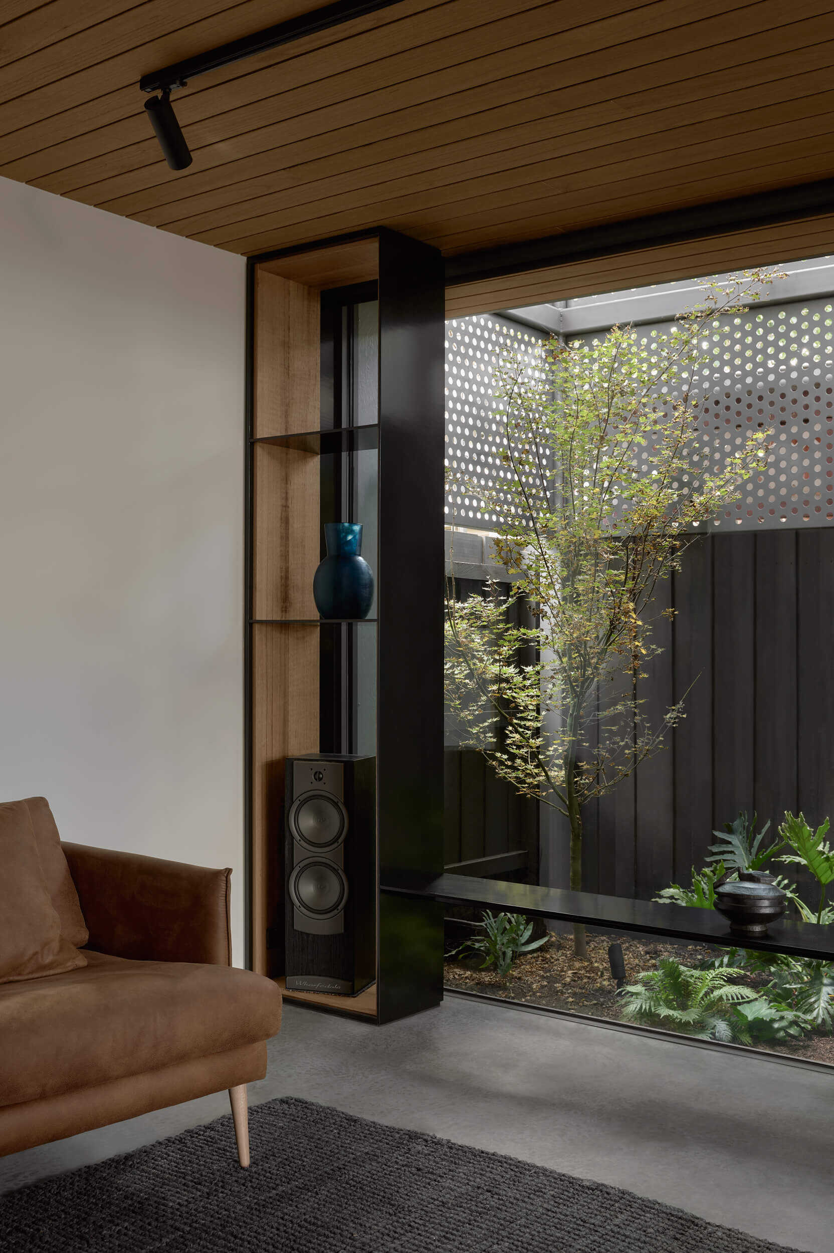 Double-height courtyards, perforated metal screens and expansive glazing fill this Melbourne living room with natural light throughout the day.