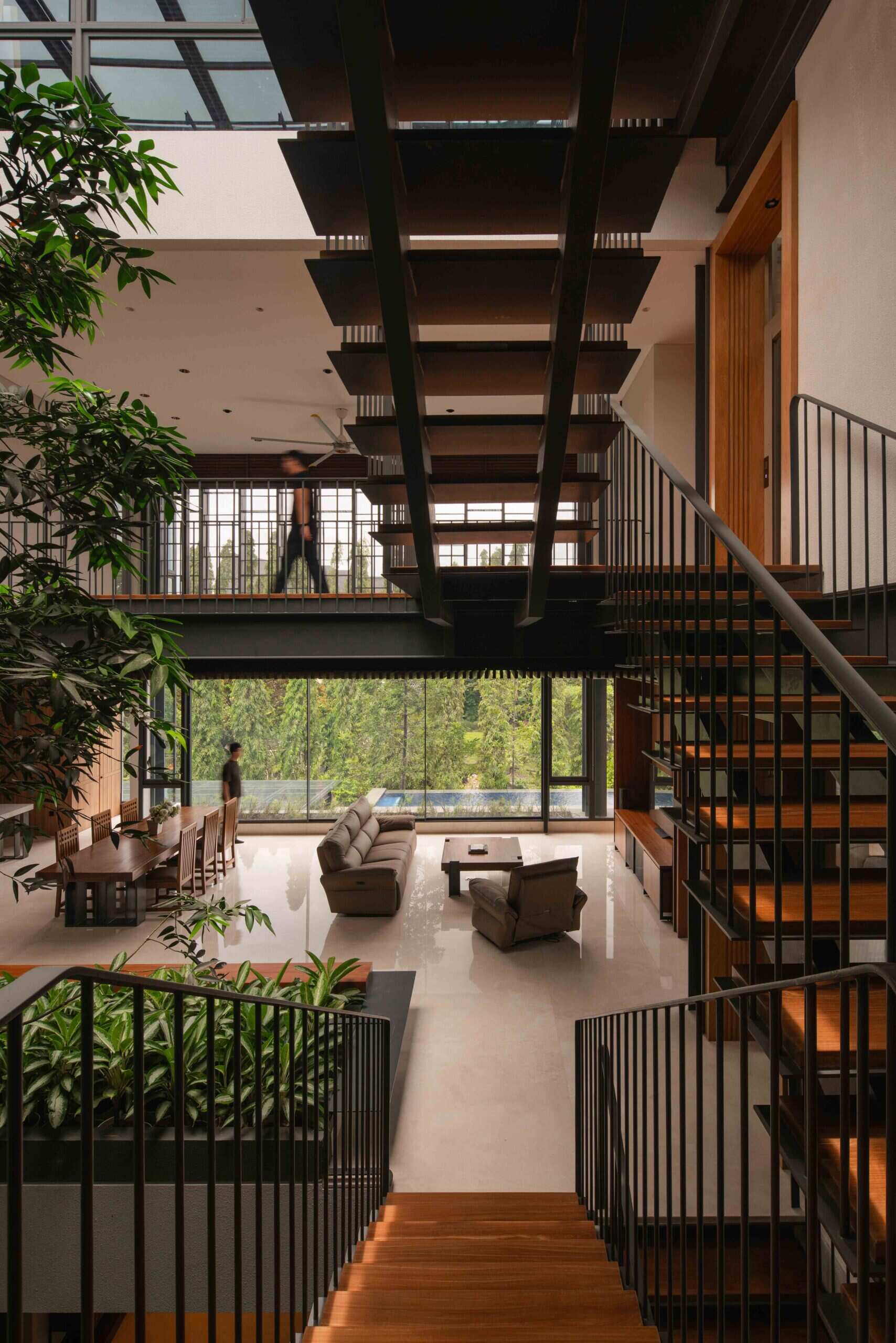 Floating steel stairs rise through a lush courtyard, creating one of the most distinctive features of this modern tropical home.
