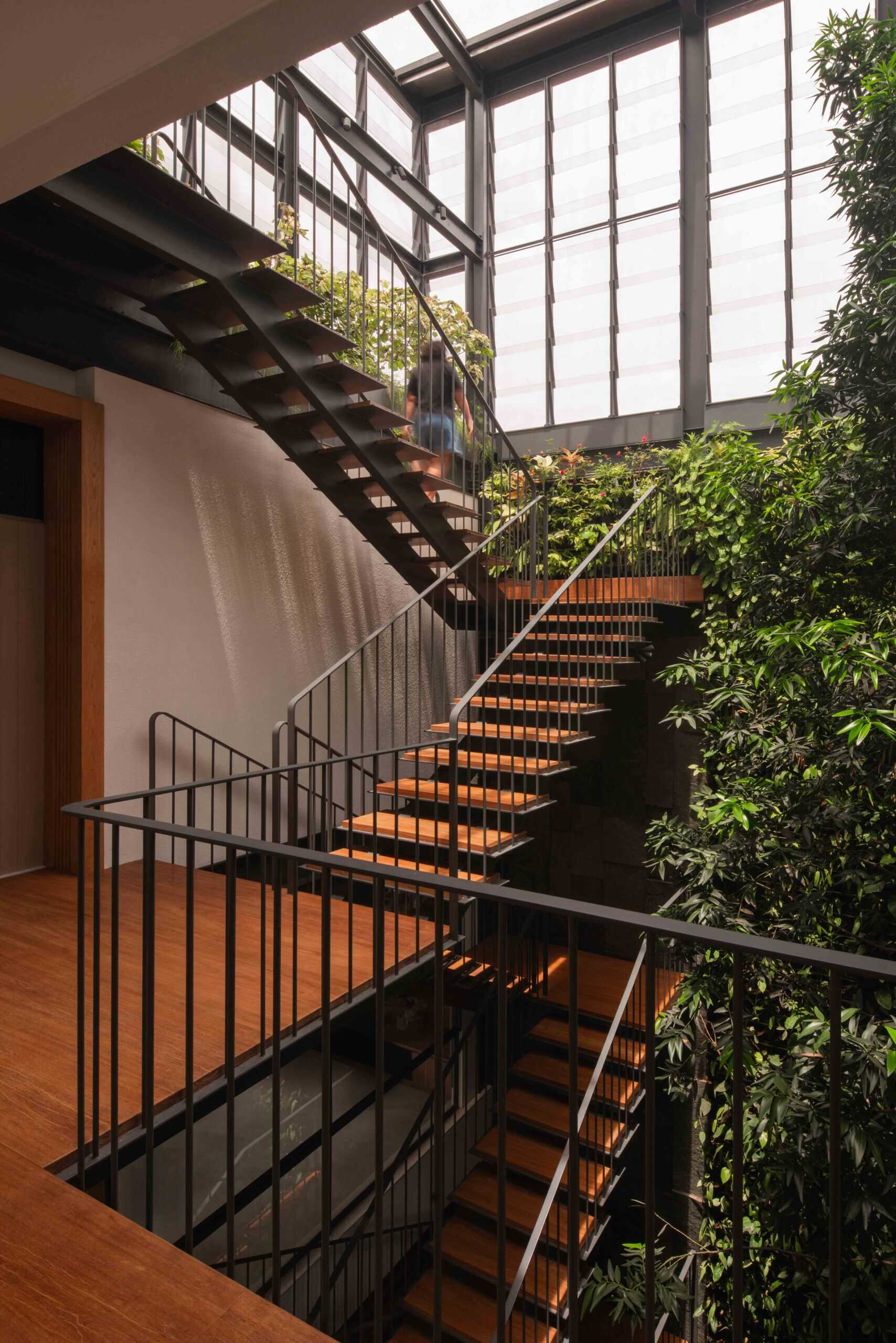 Floating steel stairs rise through a lush courtyard, creating one of the most distinctive features of this modern tropical home.