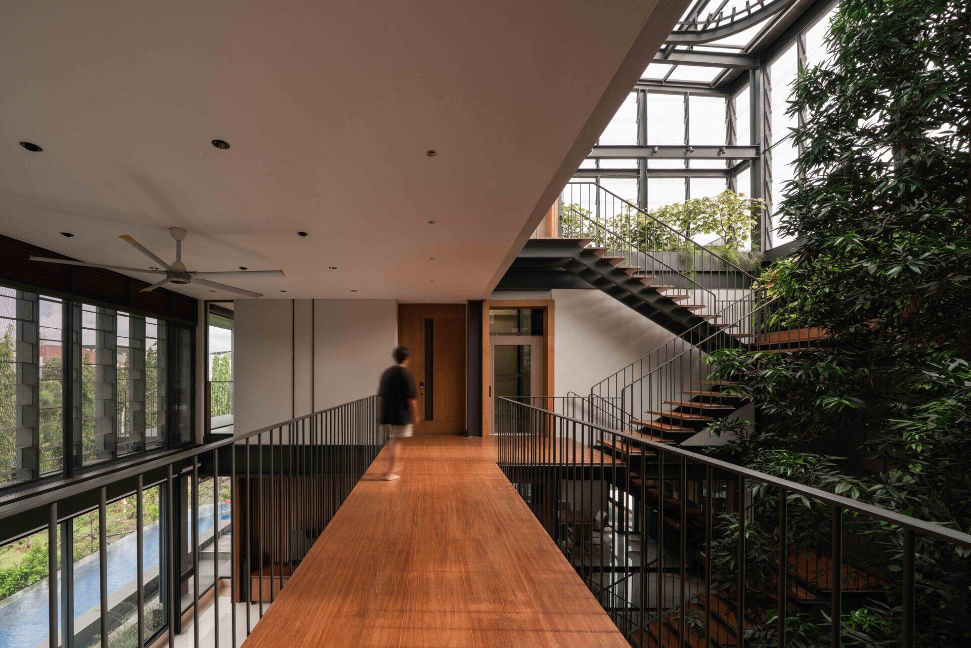 Floating steel stairs rise through a lush courtyard, creating one of the most distinctive features of this modern tropical home.