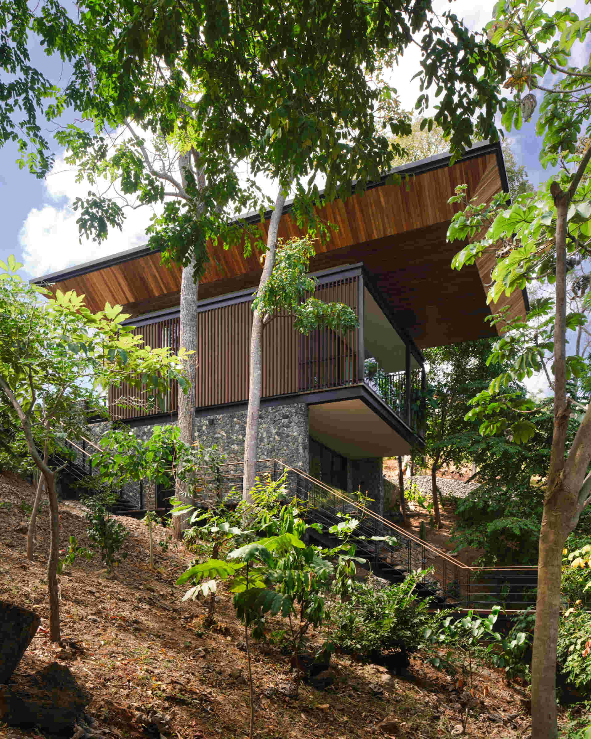 See how Casa Akíga uses stone, timber, and a floating roof to create a modern home shaped by Costa Rica's natural terrain.