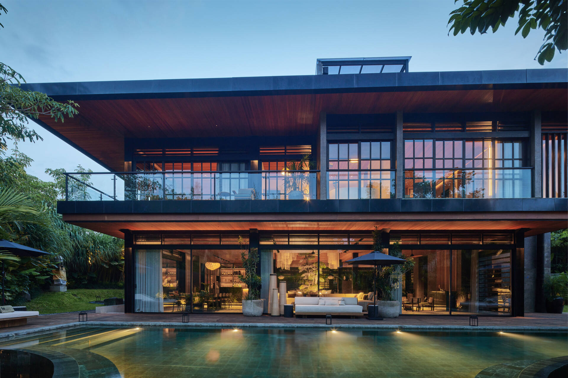 A second swimming pool with a curved edge, extends alongside this open ground-floor setting, reinforcing the connection between indoor and outdoor living. Positioned beside the social spaces, the water reflects changing light throughout the day while adding another layer of openness to the design.
