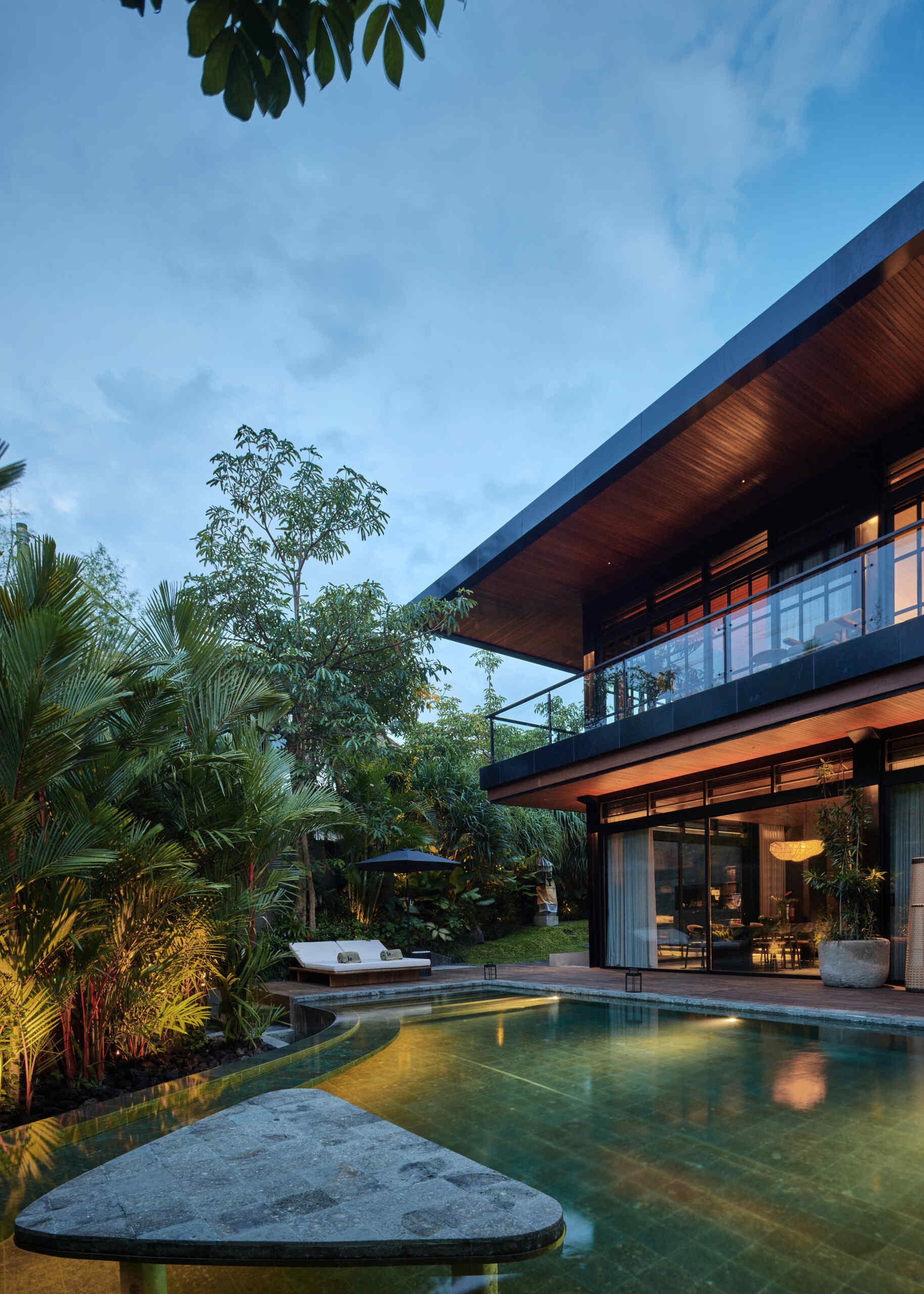 A second swimming pool with a curved edge, extends alongside this open ground-floor setting, reinforcing the connection between indoor and outdoor living. Positioned beside the social spaces, the water reflects changing light throughout the day while adding another layer of openness to the design.