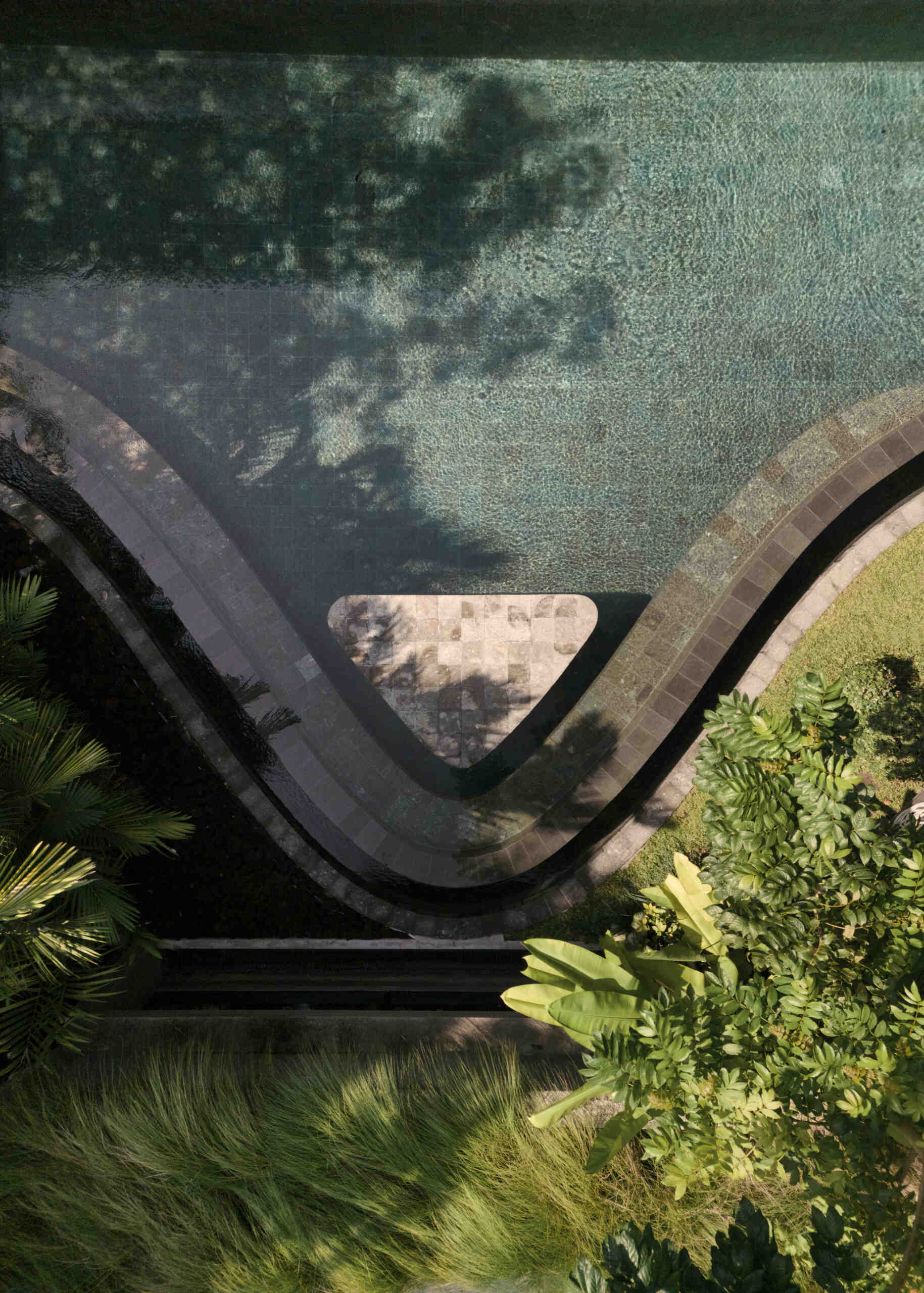 A second swimming pool with a curved edge, extends alongside this open ground-floor setting, reinforcing the connection between indoor and outdoor living. Positioned beside the social spaces, the water reflects changing light throughout the day while adding another layer of openness to the design.