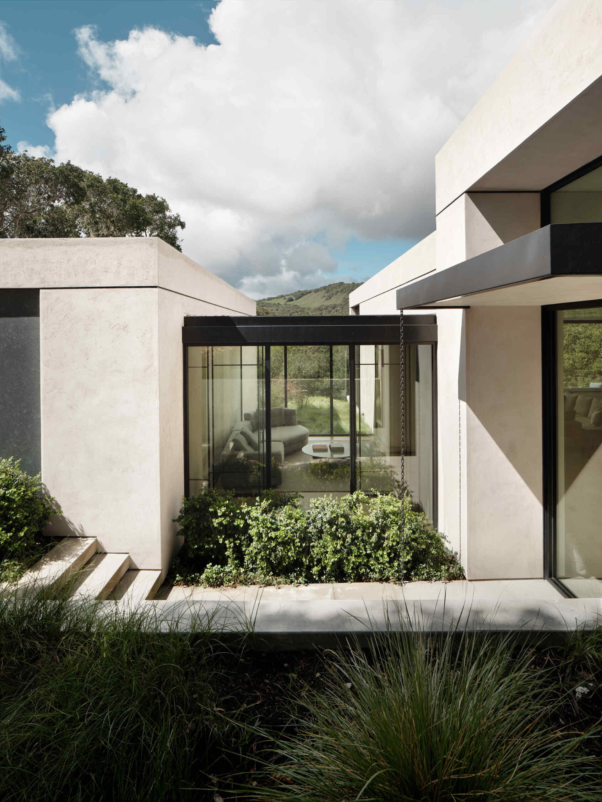La carretera que conduce a Live Oak Residence convierte una simple caminata desde la pista de motor en una experiencia arquitectónica a través de robles y senderos en las laderas.