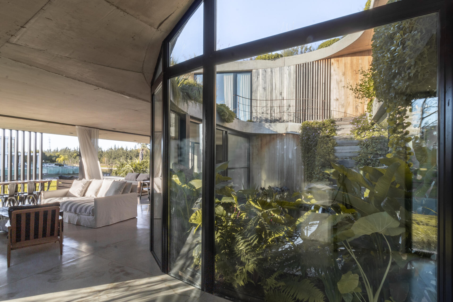 Curved glass, water reflections, and lagoon views make this modern living room one of the standout spaces inside GP House.