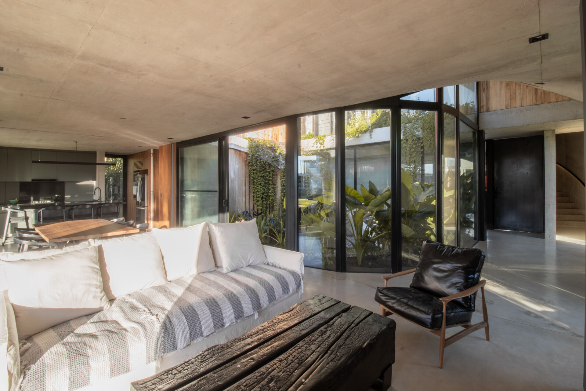 Curved glass, water reflections, and lagoon views make this modern living room one of the standout spaces inside GP House.