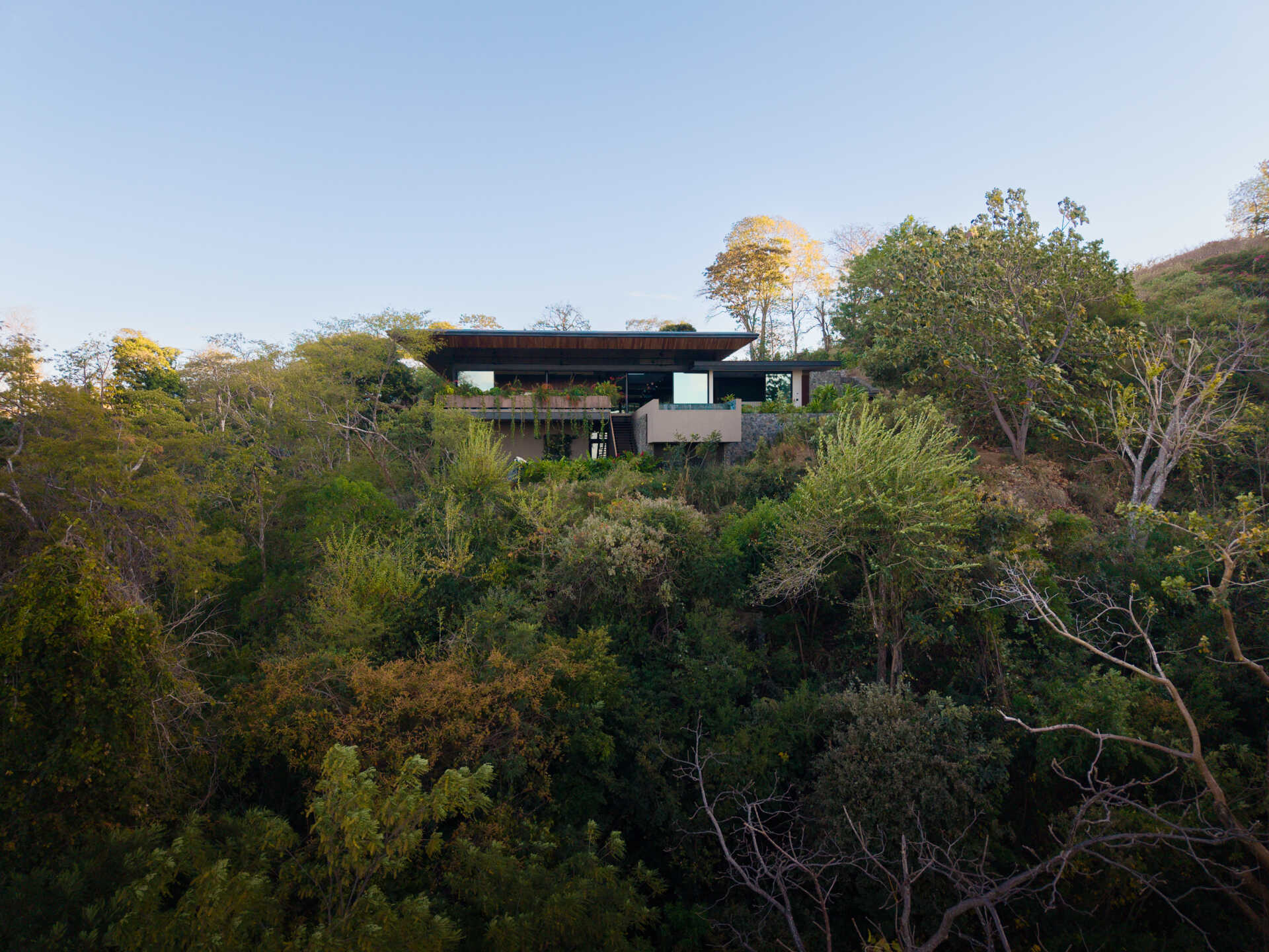 See how Casa Akíga uses stone, timber, and a floating roof to create a modern home shaped by Costa Rica's natural terrain.