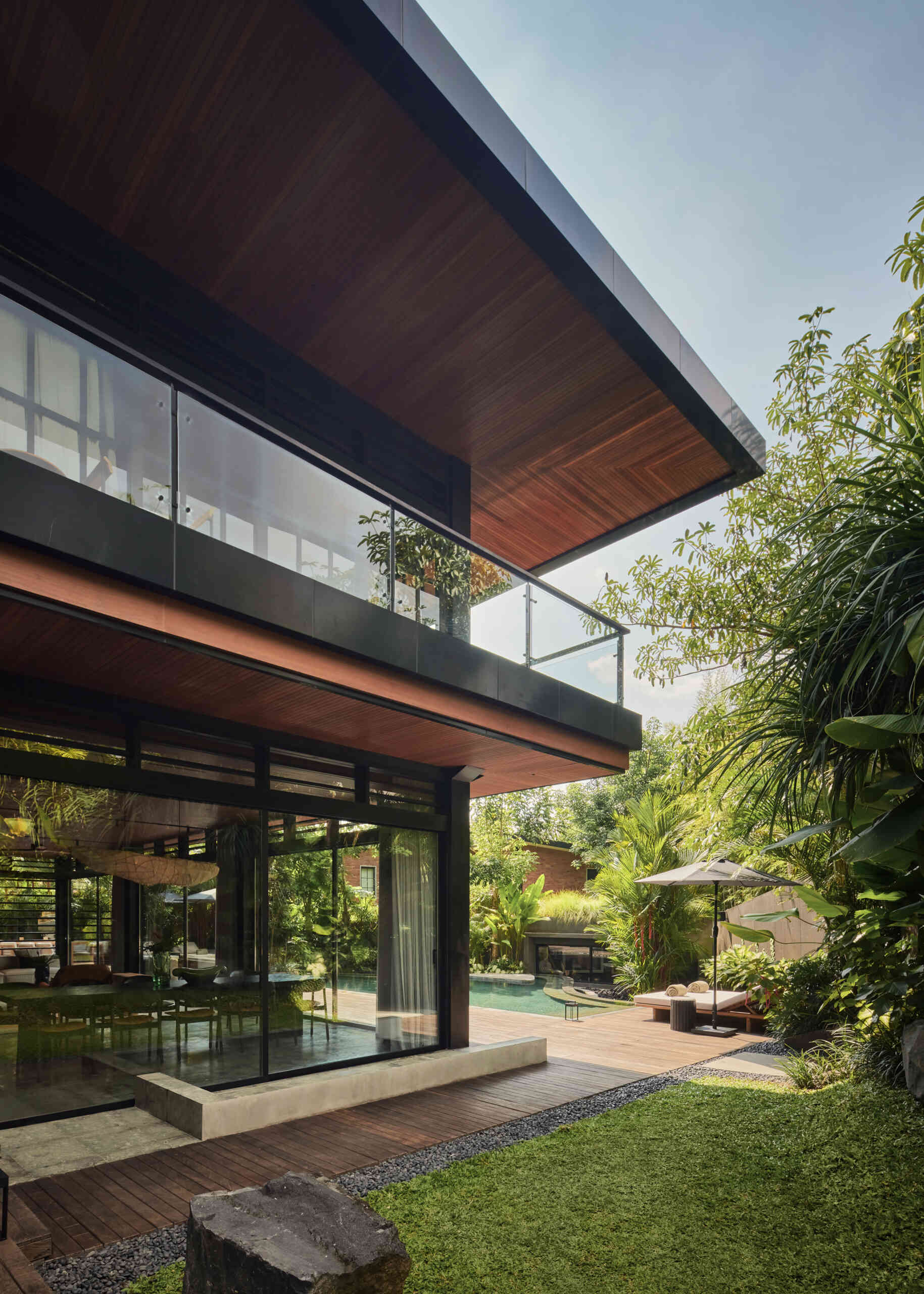 A second swimming pool with a curved edge, extends alongside this open ground-floor setting, reinforcing the connection between indoor and outdoor living. Positioned beside the social spaces, the water reflects changing light throughout the day while adding another layer of openness to the design.