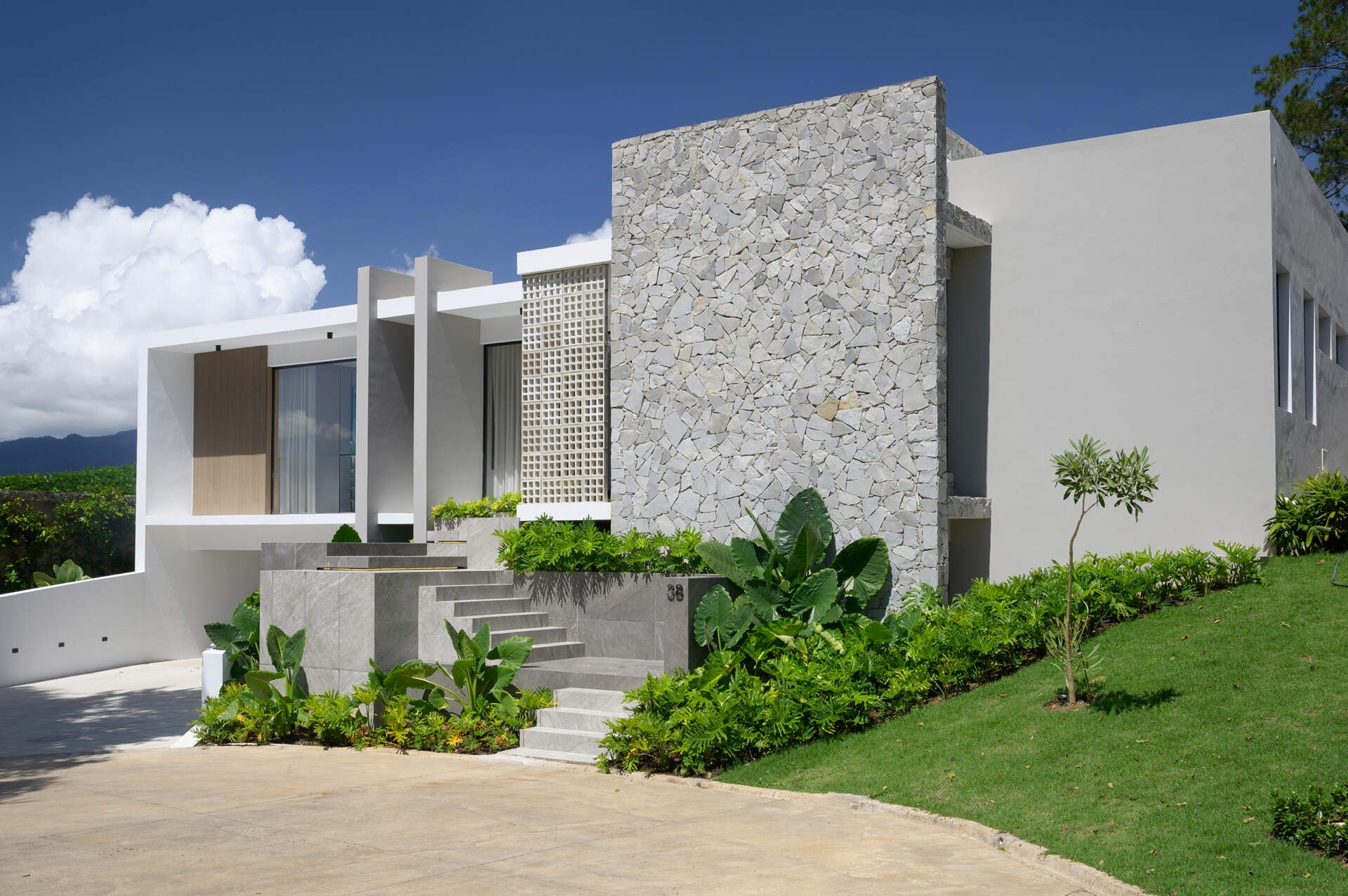 Discover how Casa L.A. uses natural stone, timber, perforated masonry and floor-to-ceiling glazing to create a modern tropical home that follows the hillside.