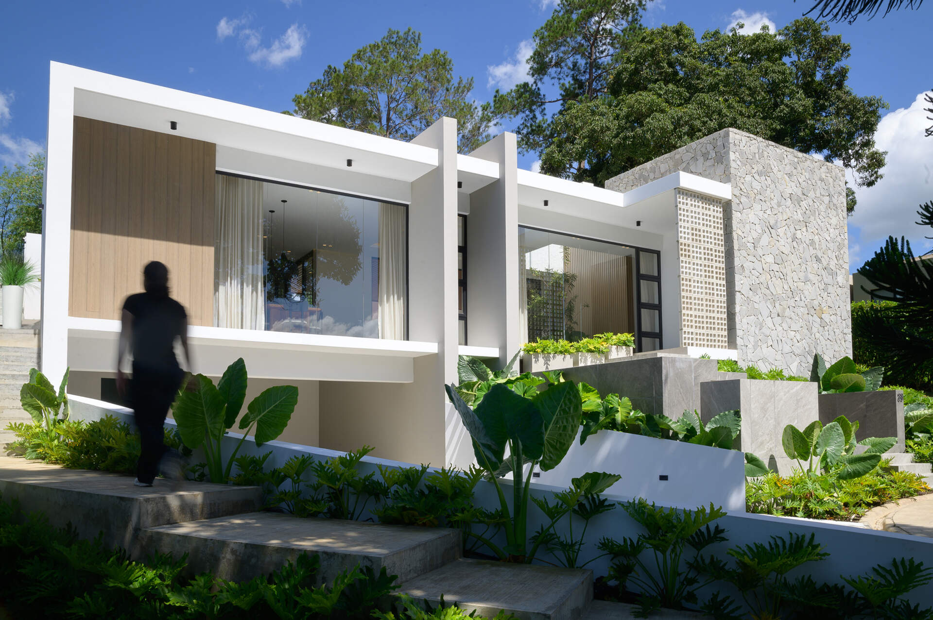 Discover how Casa L.A. uses natural stone, timber, perforated masonry and floor-to-ceiling glazing to create a modern tropical home that follows the hillside.