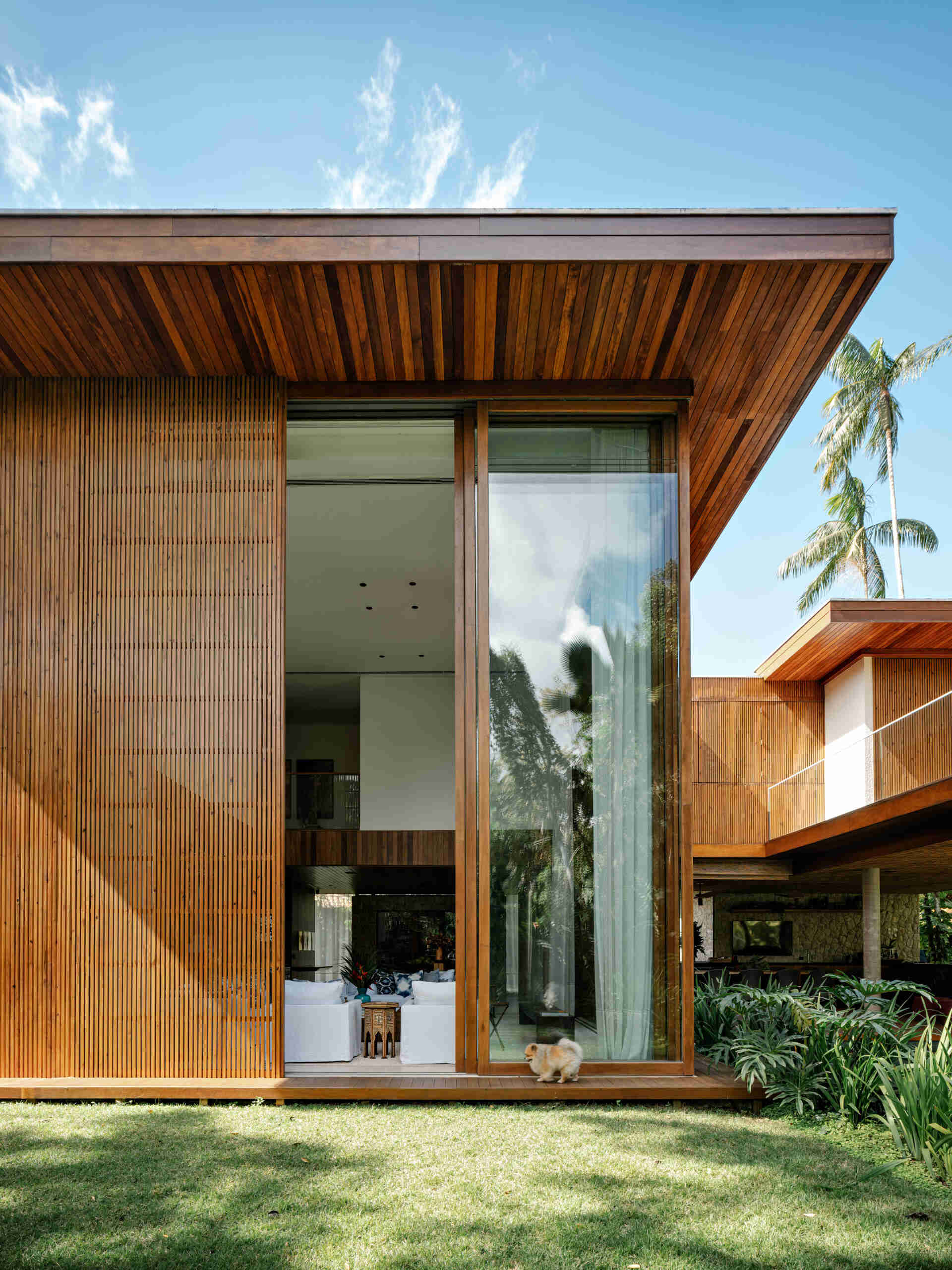 See how towering glass walls and a dramatic double-height ceiling transform this modern Brazilian beach house.