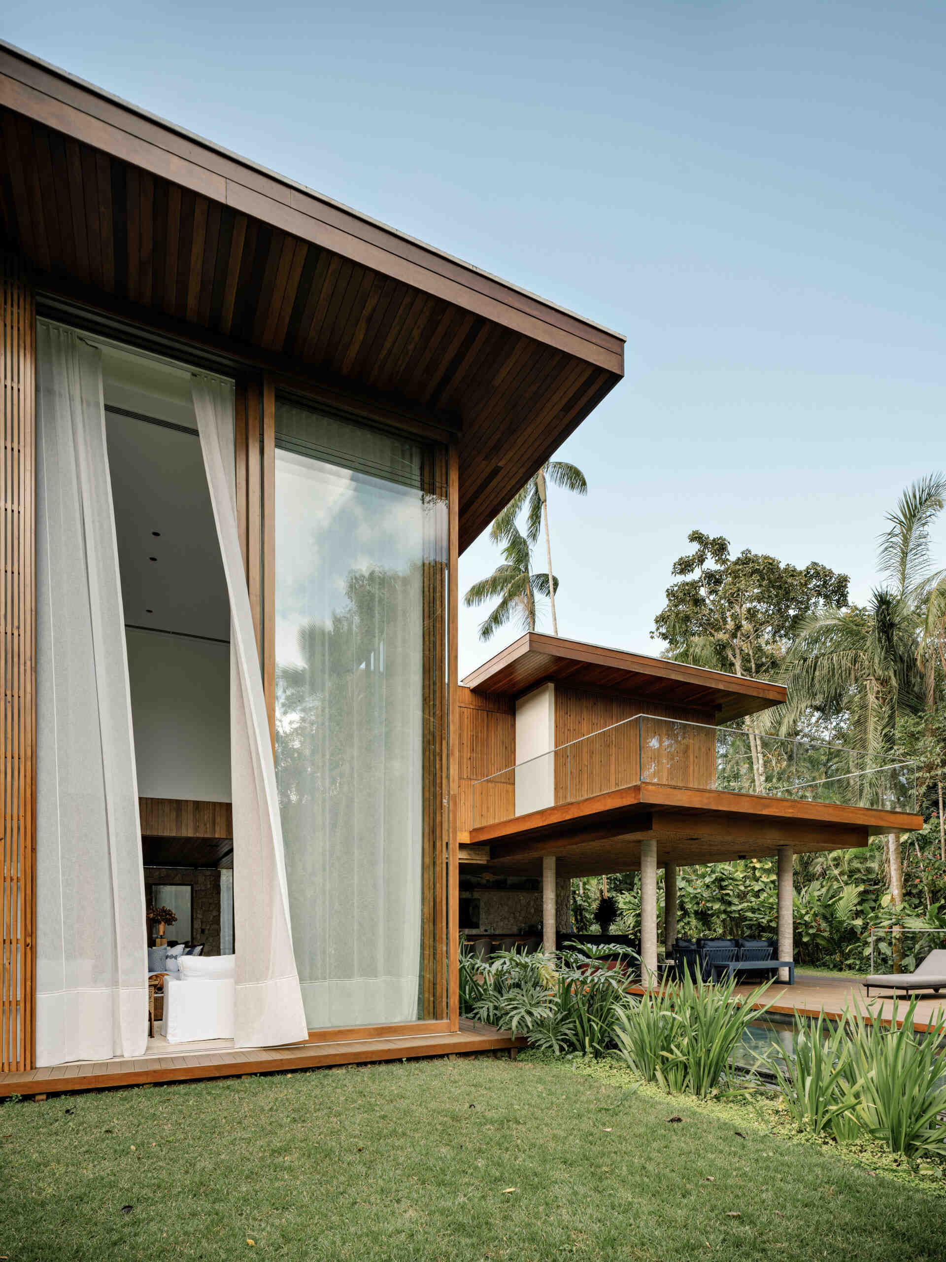 See how towering glass walls and a dramatic double-height ceiling transform this modern Brazilian beach house.