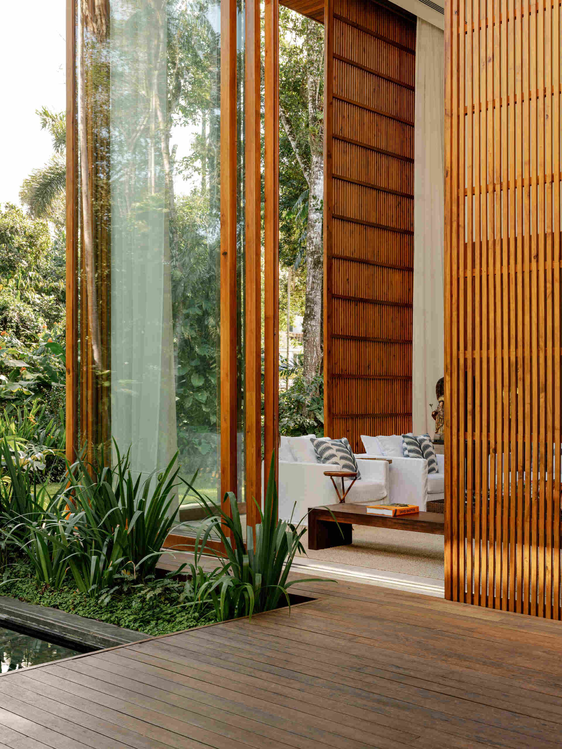 See how towering glass walls and a dramatic double-height ceiling transform this modern Brazilian beach house.