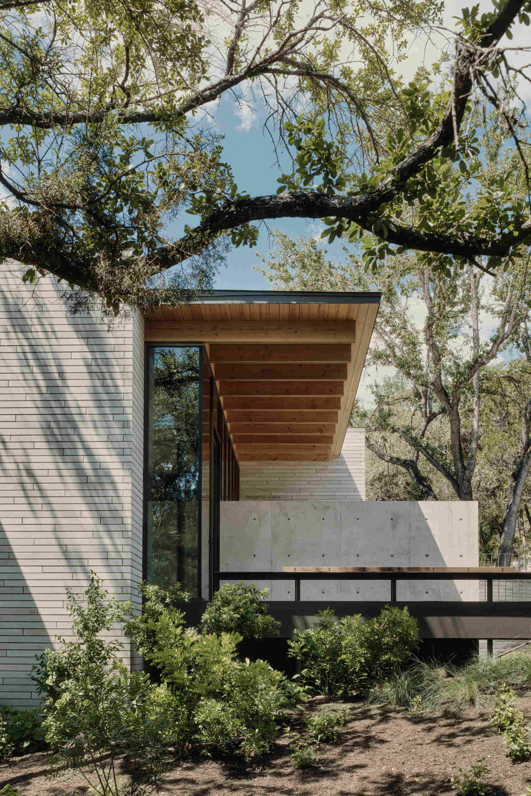 A pedestrian bridge creates a memorable entrance while revealing the home's layered architectural design.