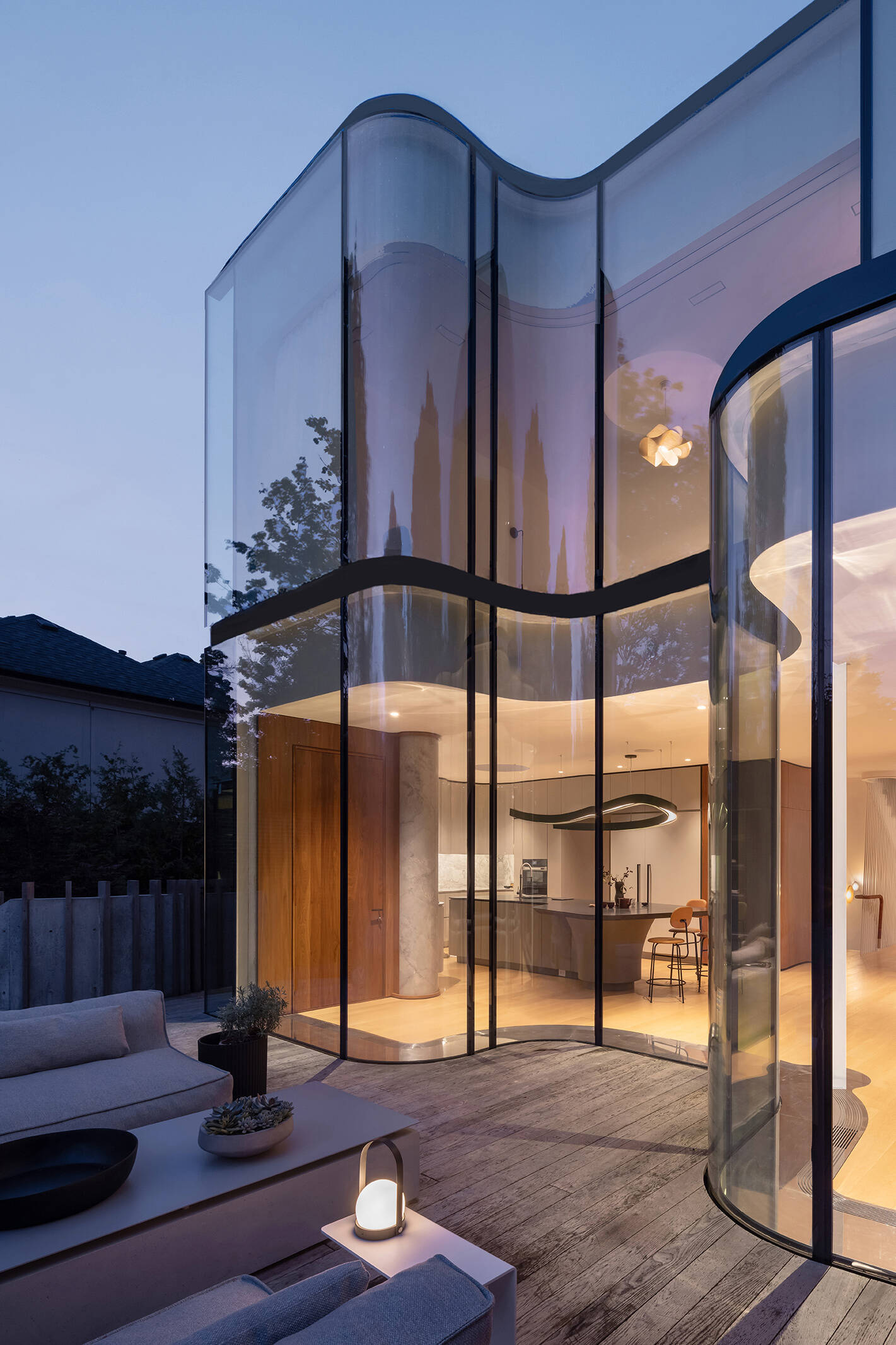 The flowing curved glass wall is the signature feature of Snider House, bringing light, transparency, and garden views deep into the home.