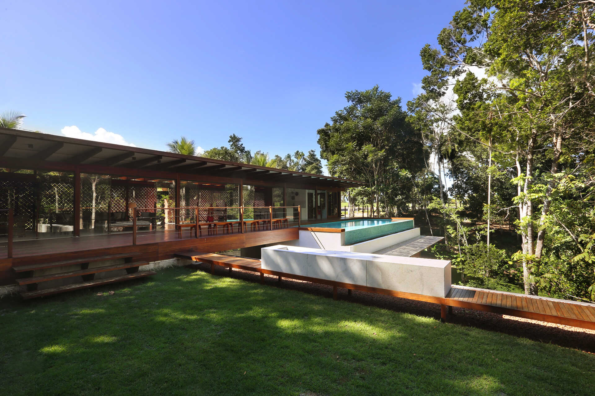 An infinity pool floats above the Atlantic Forest while a generous timber deck and wraparound bench create the perfect outdoor entertaining space.