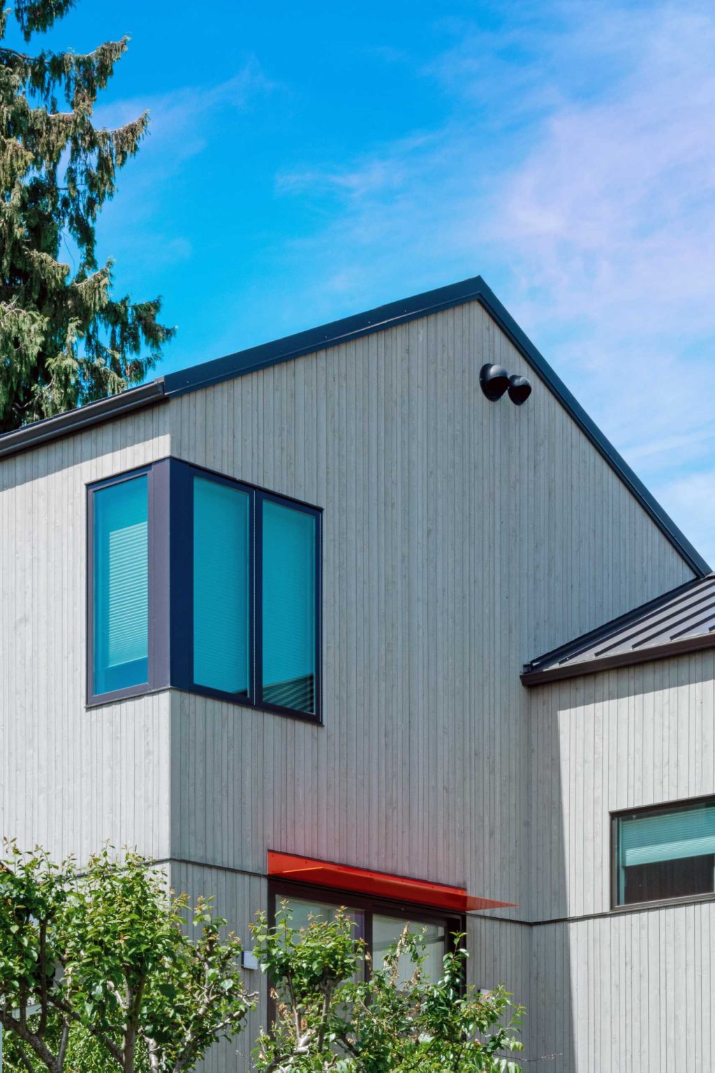 A colorful new front entry, warm wood siding, larger windows, and a welcoming façade completely change the street presence of this renovated Seattle home.