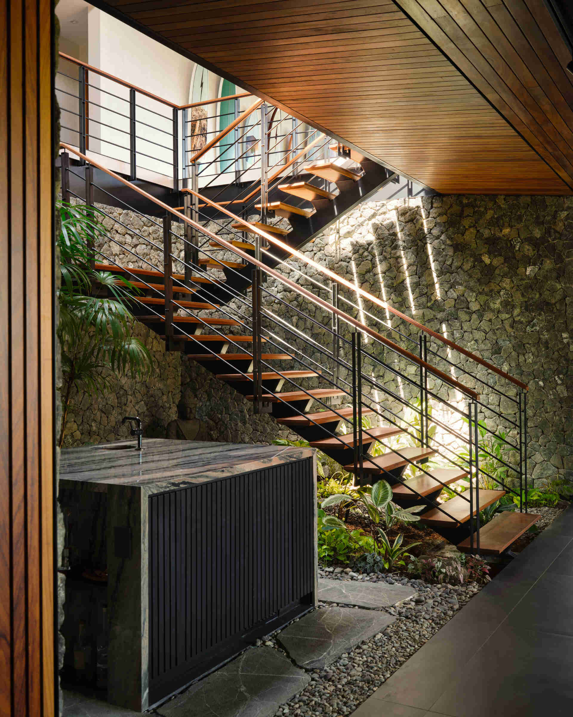 Floating timber treads, steel detailing, and lush planting transform this staircase into one of the home's standout features.