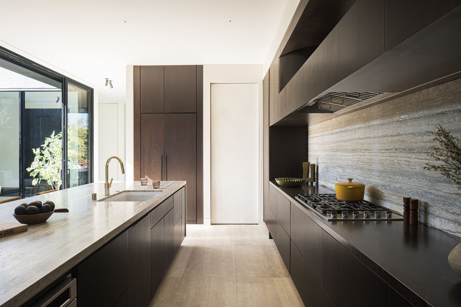 This elegant kitchen pairs rich timber cabinetry with striking natural stone, creating a warm and sophisticated space centered around a generous island for cooking and gathering.