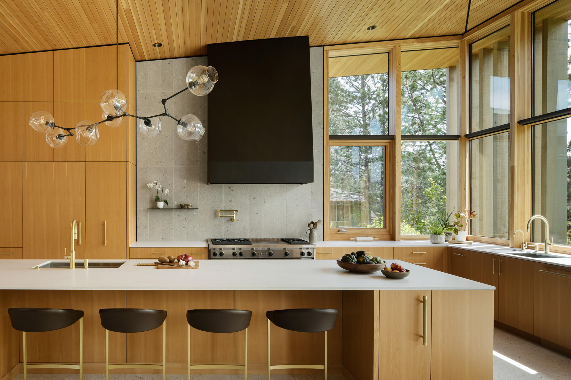 Visite la cocina moderna y luminosa con cálidos gabinetes de madera, una isla blanca y un tranquilo rincón para desayunar con vista a los árboles circundantes.
