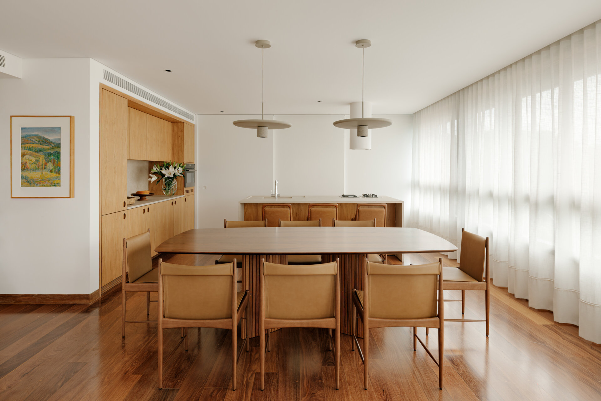 See how sliding doors, timber cabinetry and stone surfaces create a flexible kitchen that feels open yet practical.