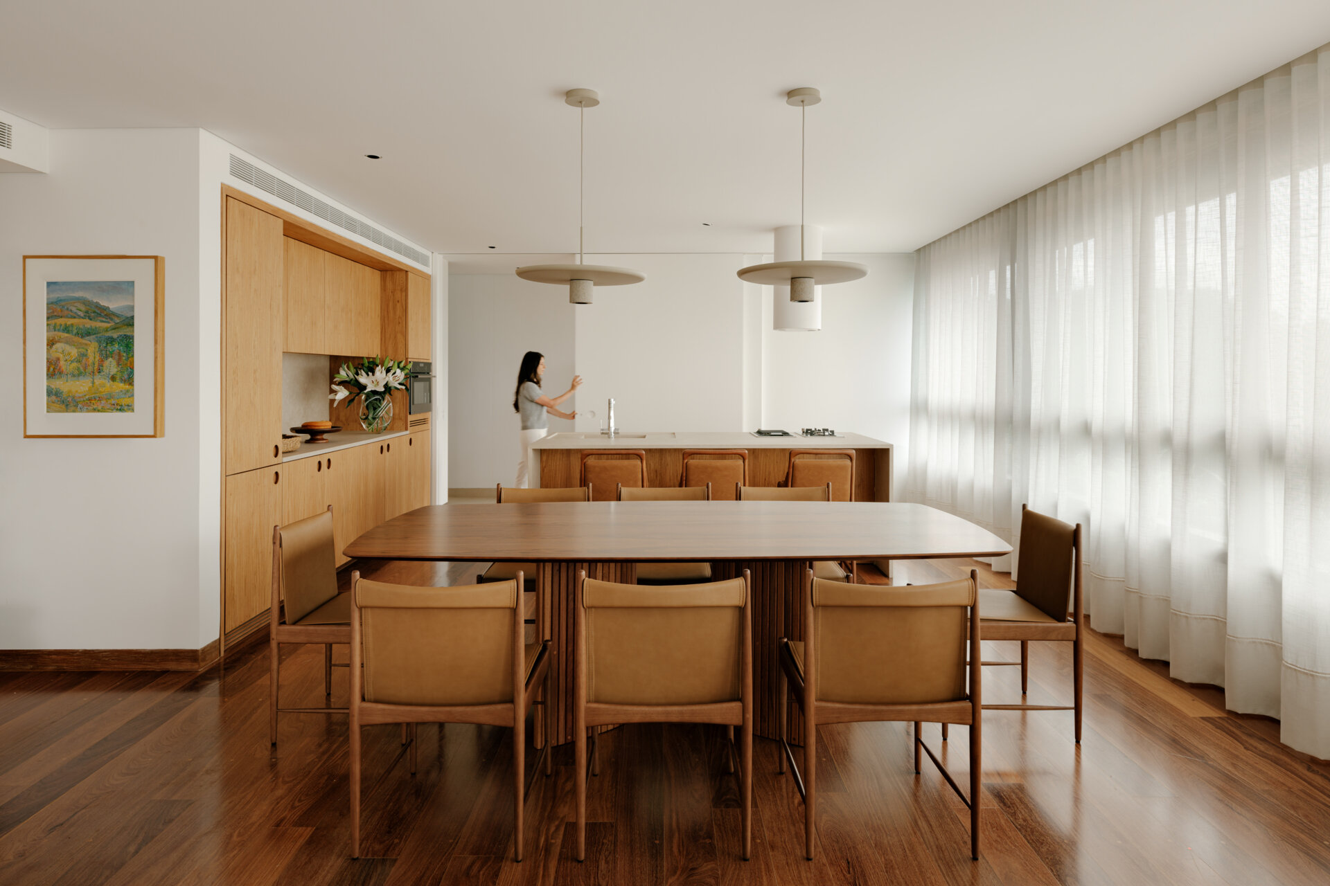 See how sliding doors, timber cabinetry and stone surfaces create a flexible kitchen that feels open yet practical.