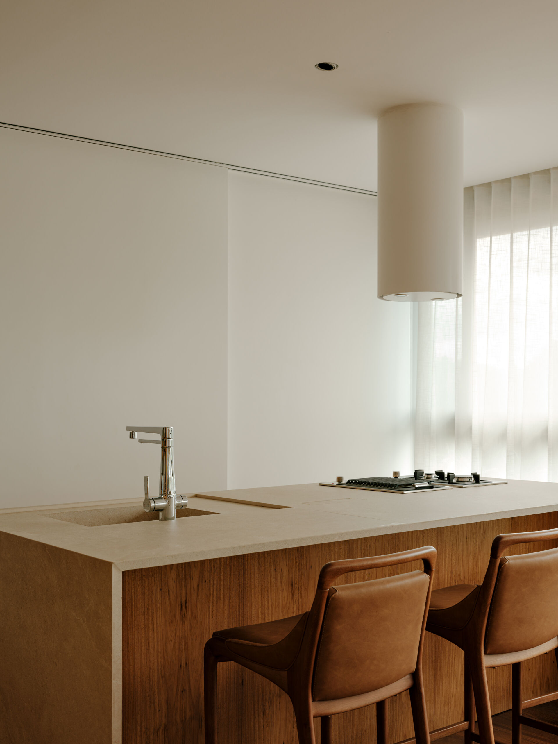 See how sliding doors, timber cabinetry and stone surfaces create a flexible kitchen that feels open yet practical.