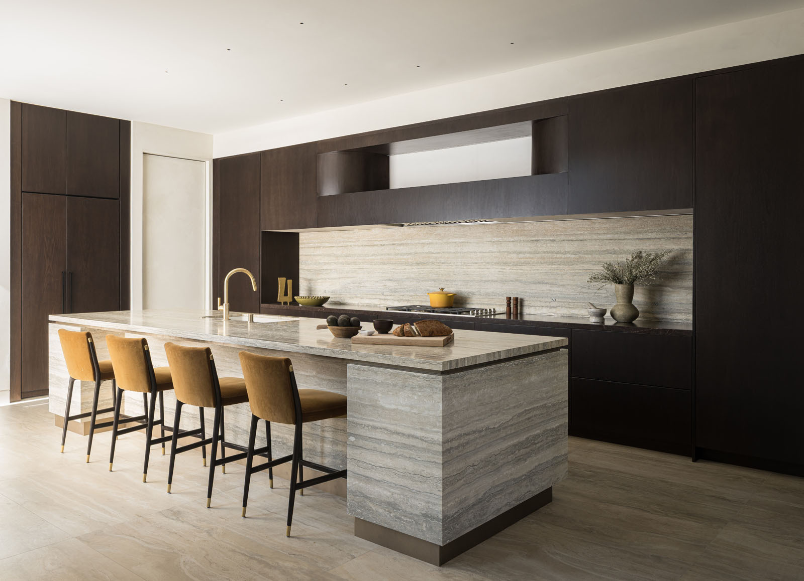 This elegant kitchen pairs rich timber cabinetry with striking natural stone, creating a warm and sophisticated space centered around a generous island for cooking and gathering.