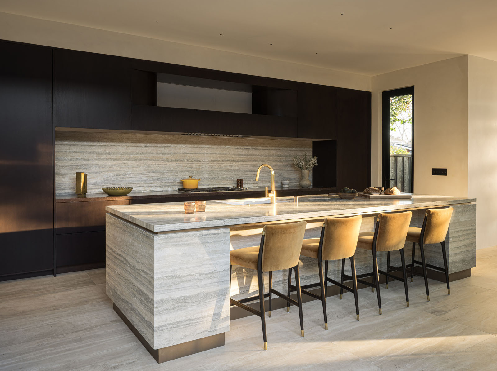 This elegant kitchen pairs rich timber cabinetry with striking natural stone, creating a warm and sophisticated space centered around a generous island for cooking and gathering.