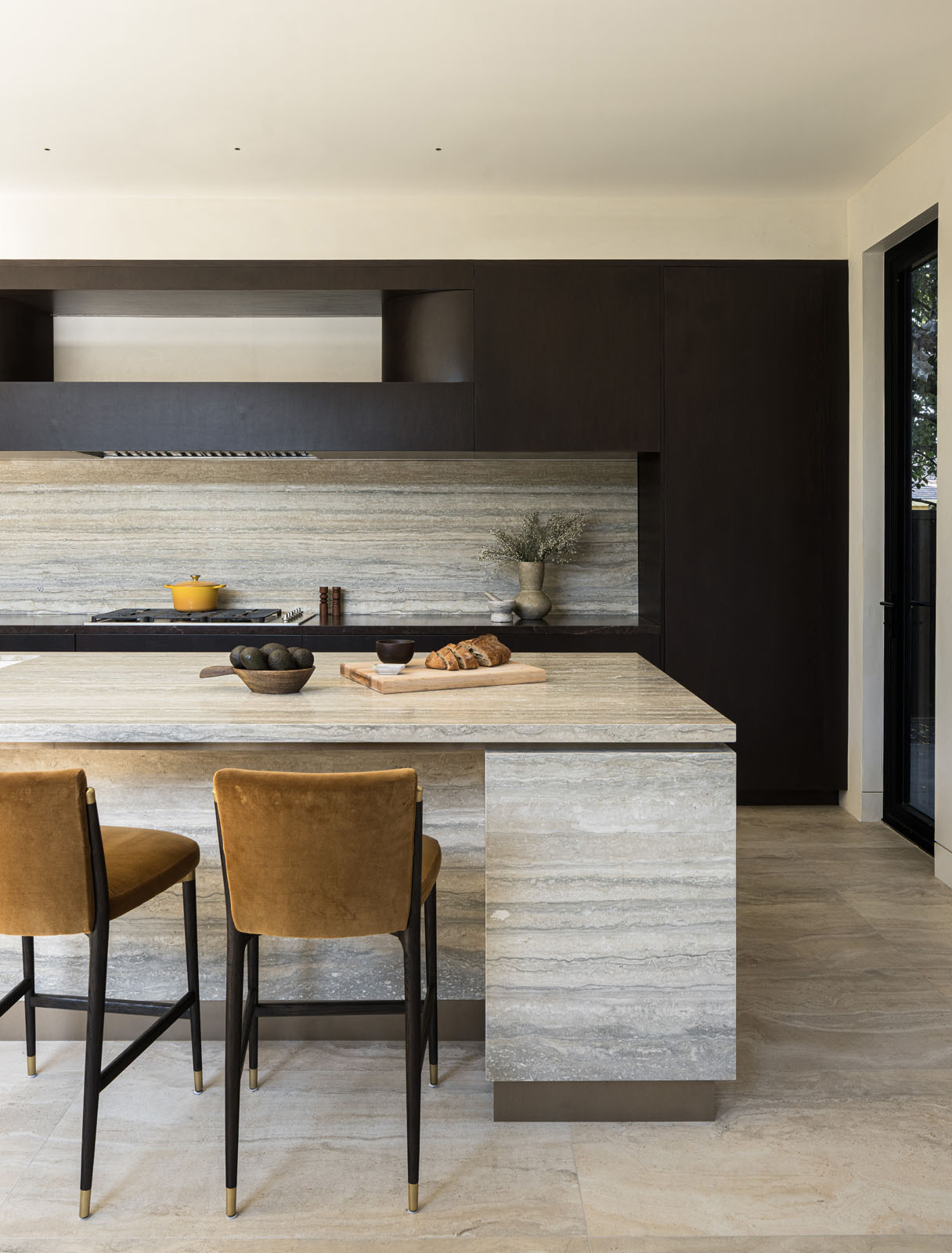 This elegant kitchen pairs rich timber cabinetry with striking natural stone, creating a warm and sophisticated space centered around a generous island for cooking and gathering.