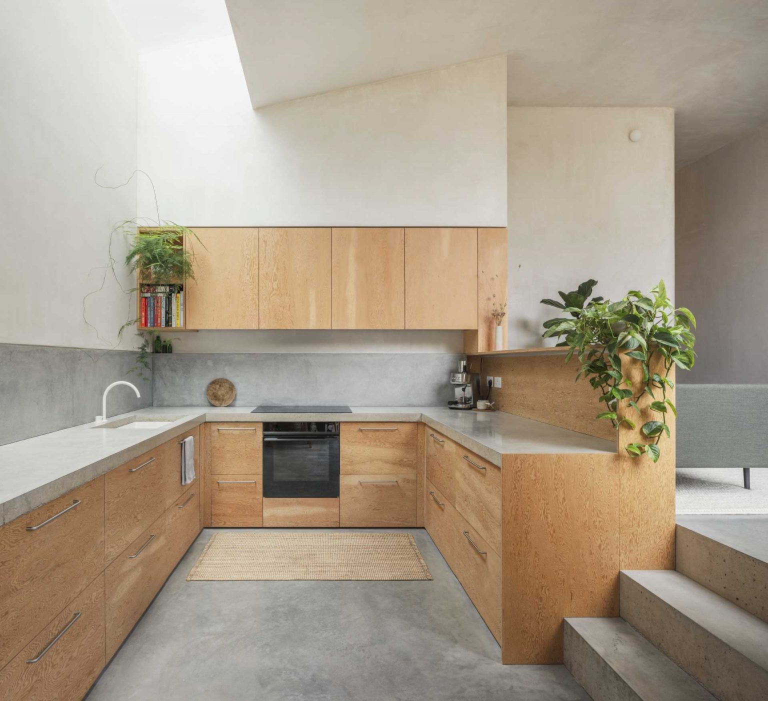 A cast concrete countertop, Douglas fir plywood cabinetry, and a long skylight fill this modern kitchen with texture and daylight while a split level creates extra ceiling height.