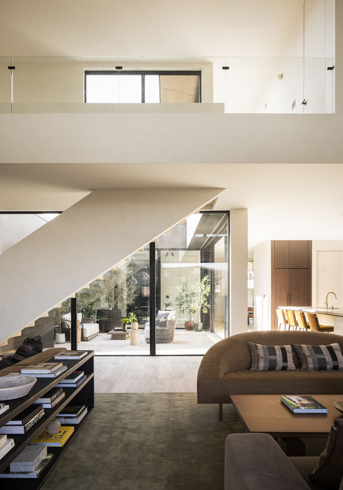 Step inside a bright double-height living room where floor-to-ceiling glazing frames a mature redwood tree, filling this modern Silicon Valley home with natural light and garden views.