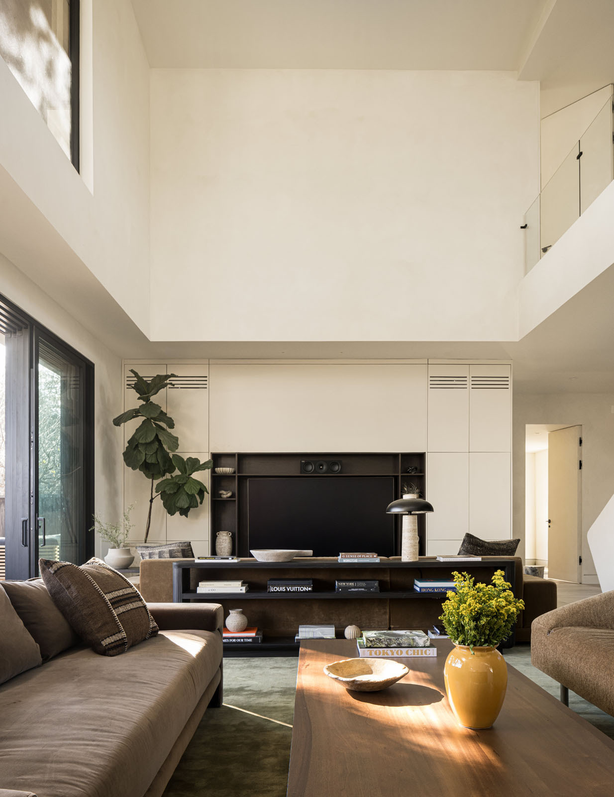Step inside a bright double-height living room where floor-to-ceiling glazing frames a mature redwood tree, filling this modern Silicon Valley home with natural light and garden views.